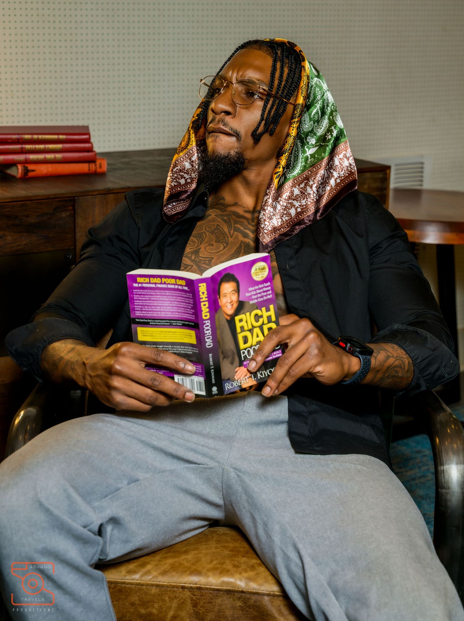 A person lounges on a brown leather couch while reading a colorful children's book.