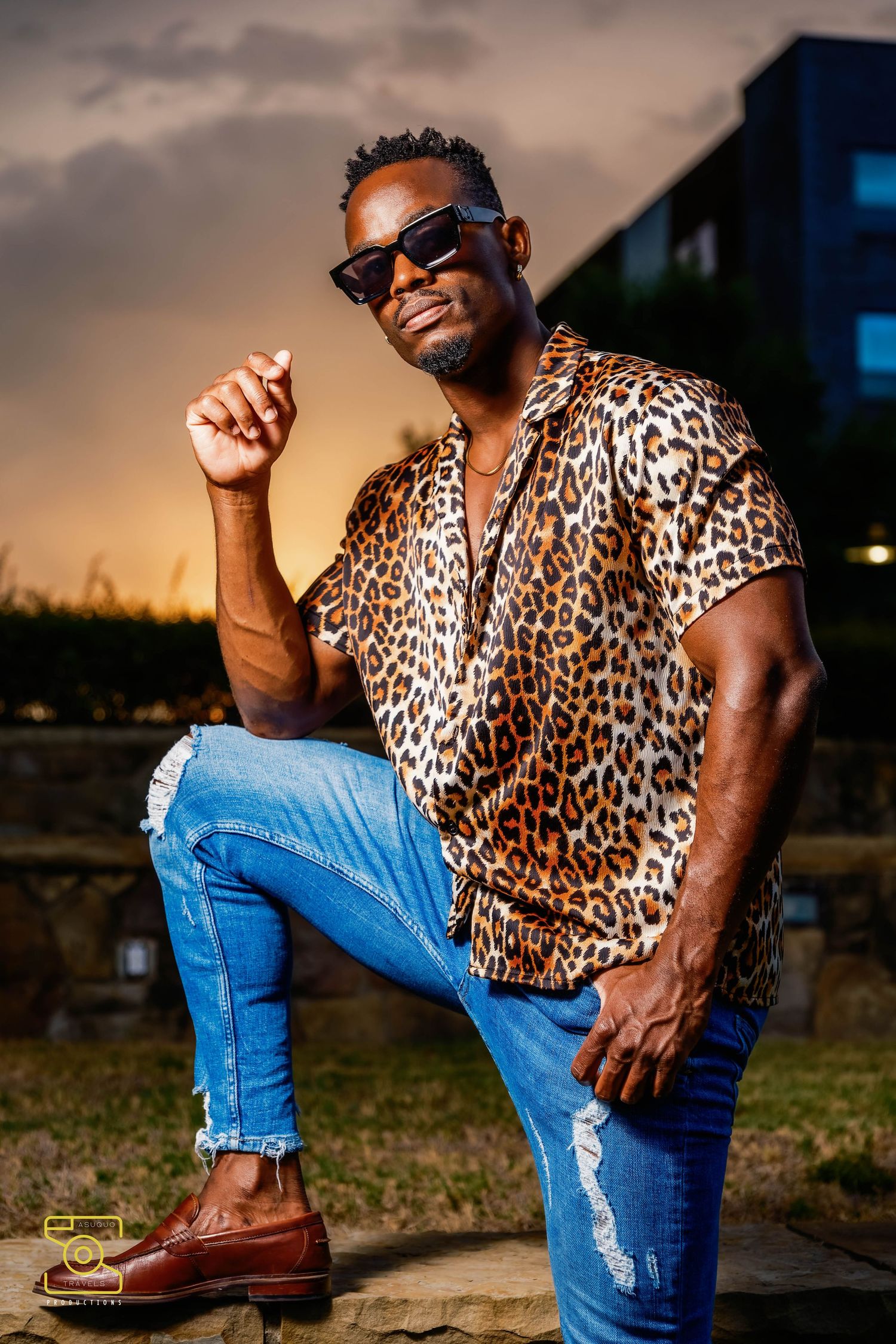 A stylish outfit featuring a leopard print shirt paired with distressed blue jeans and brown leather boots at sunset.