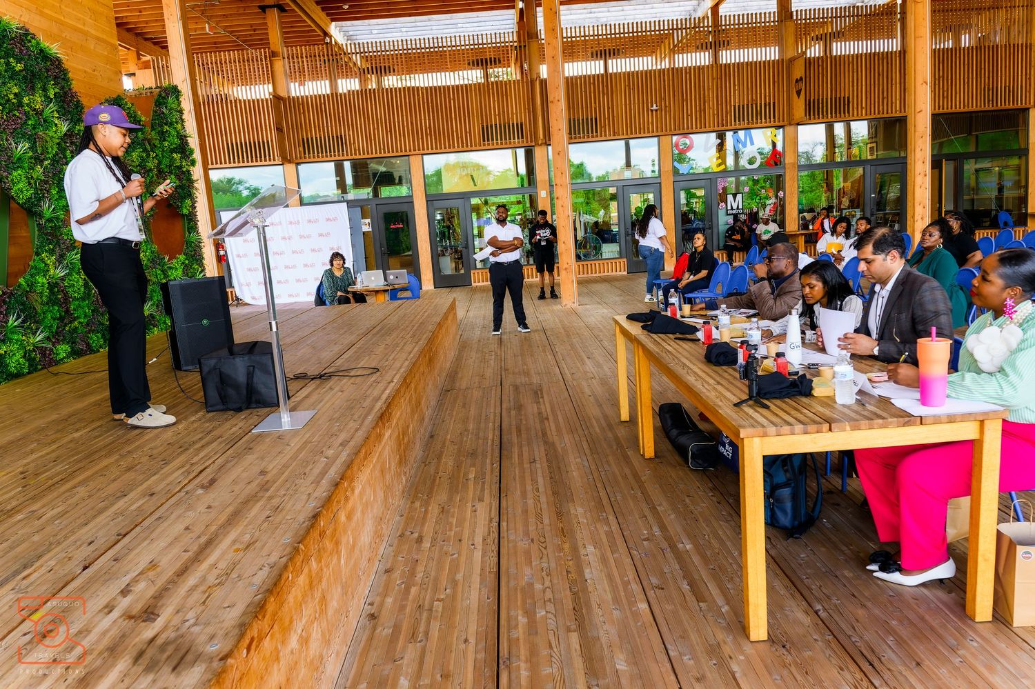 Groups of people participate in team building activities under a wooden pavilion shelter outdoors.