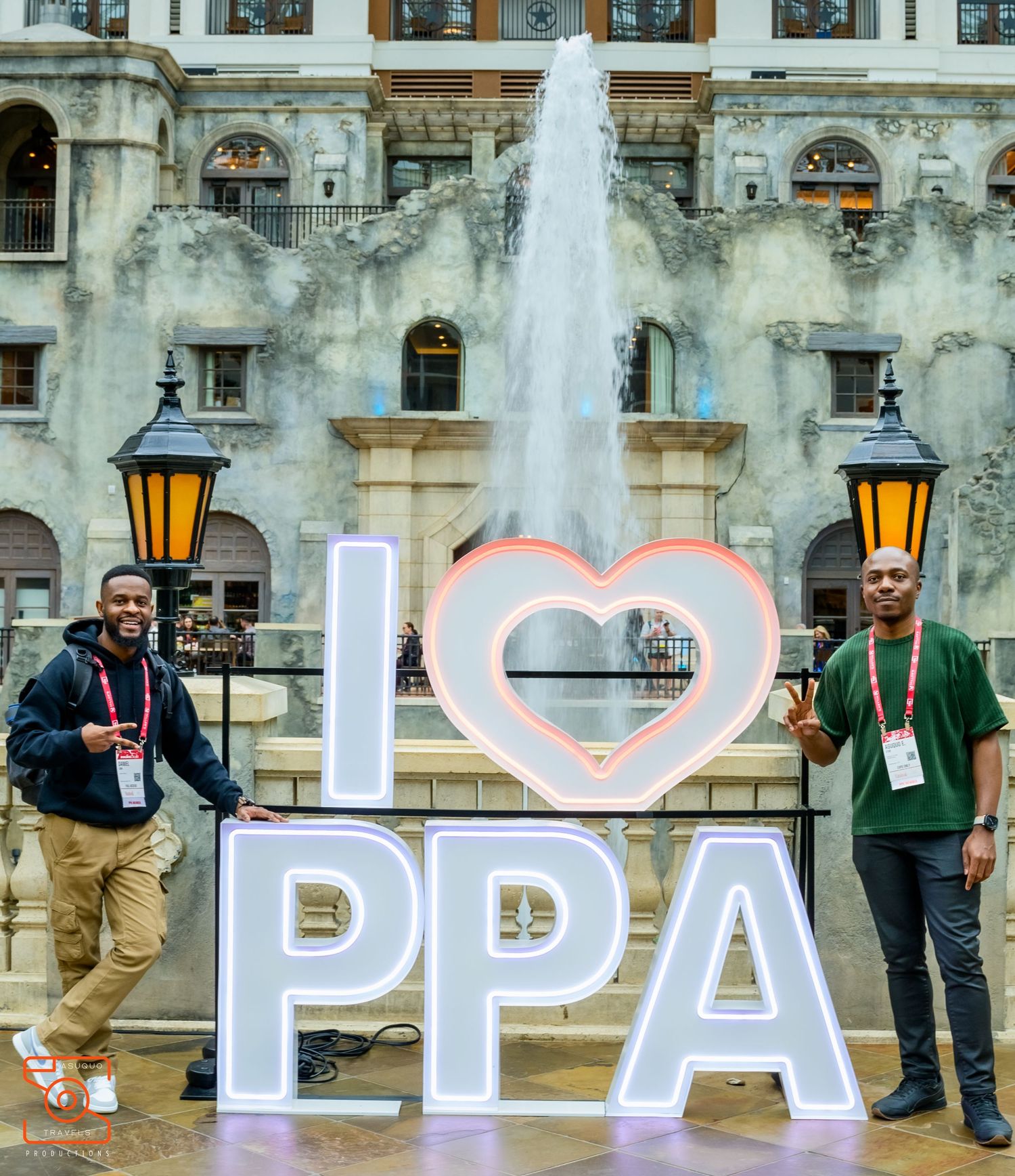 Large illuminated letters spelling PPA displayed outdoors with architectural elements in background.