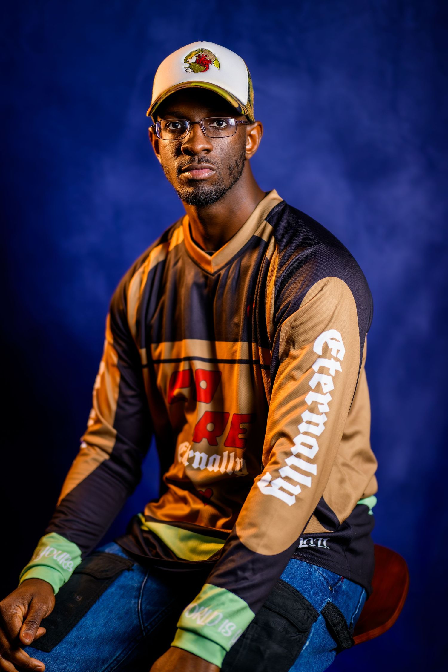 A series of fashion portraits showing someone wearing a two-tone black and brown varsity jacket with jeans against a dark blue background.