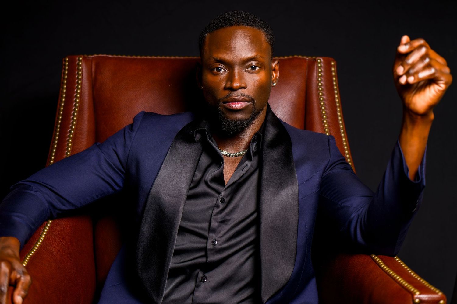 Professional portrait series in dark lighting with leather chair and formal attire.