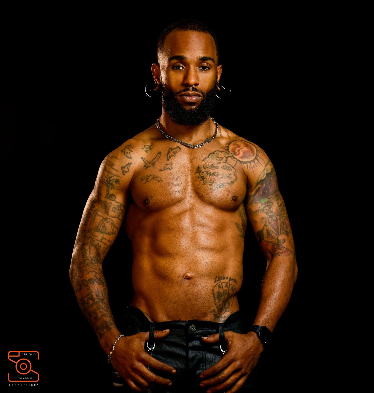 Athletic person with tattoos posing shirtless against dark background in dramatic lighting.