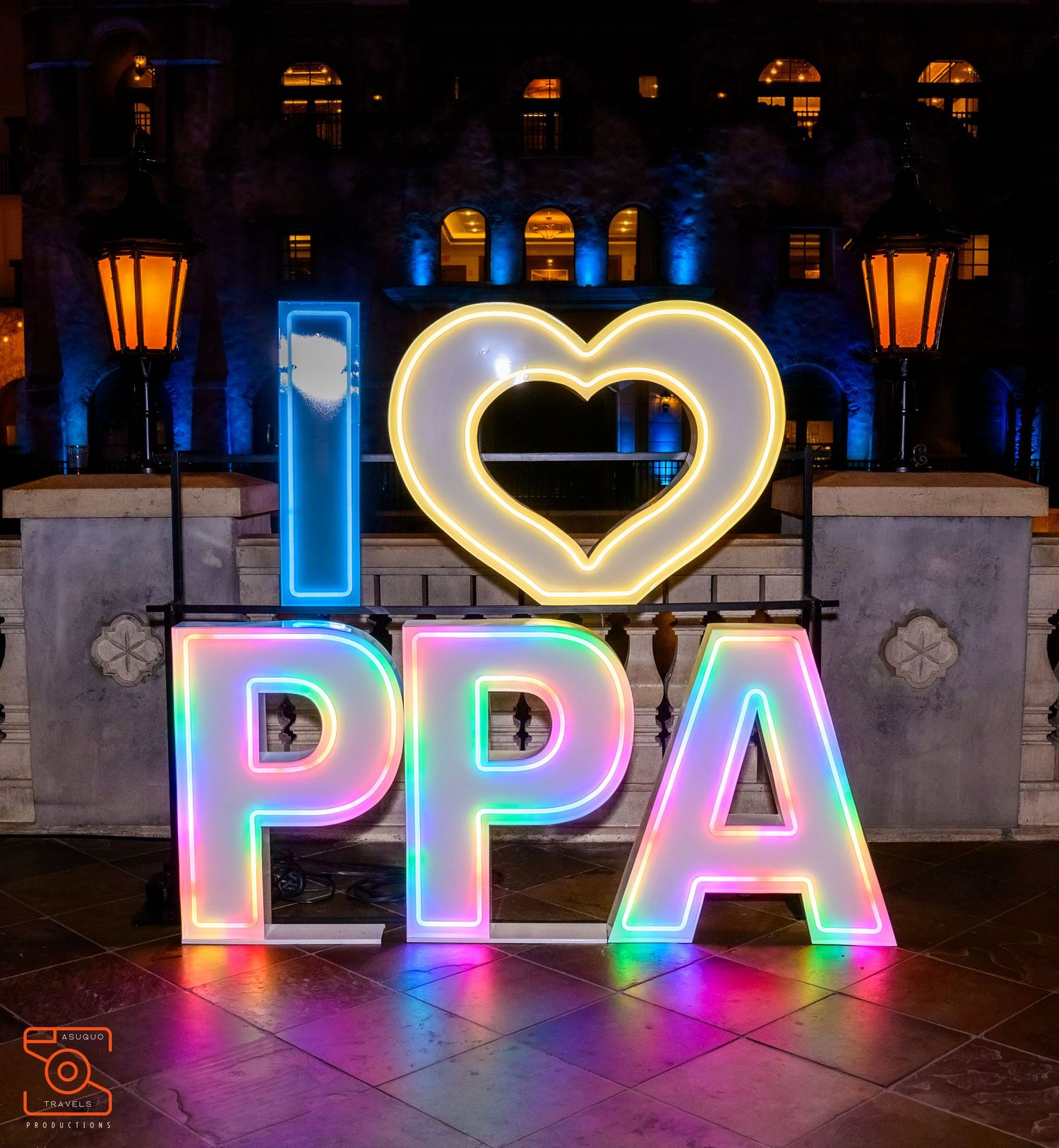 Illuminated PPA sign with heart symbol glowing in pink and blue lights at night.