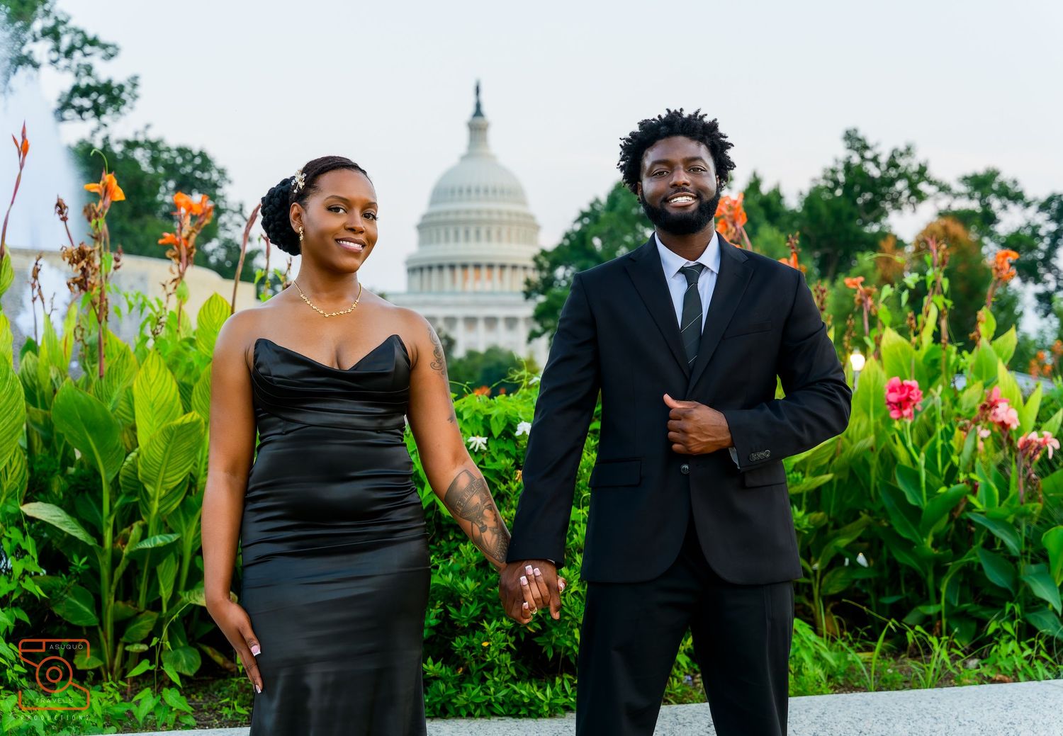 Couple in black formal wear posing in front of the U.S. Capitol building surrounded by lush gardens.