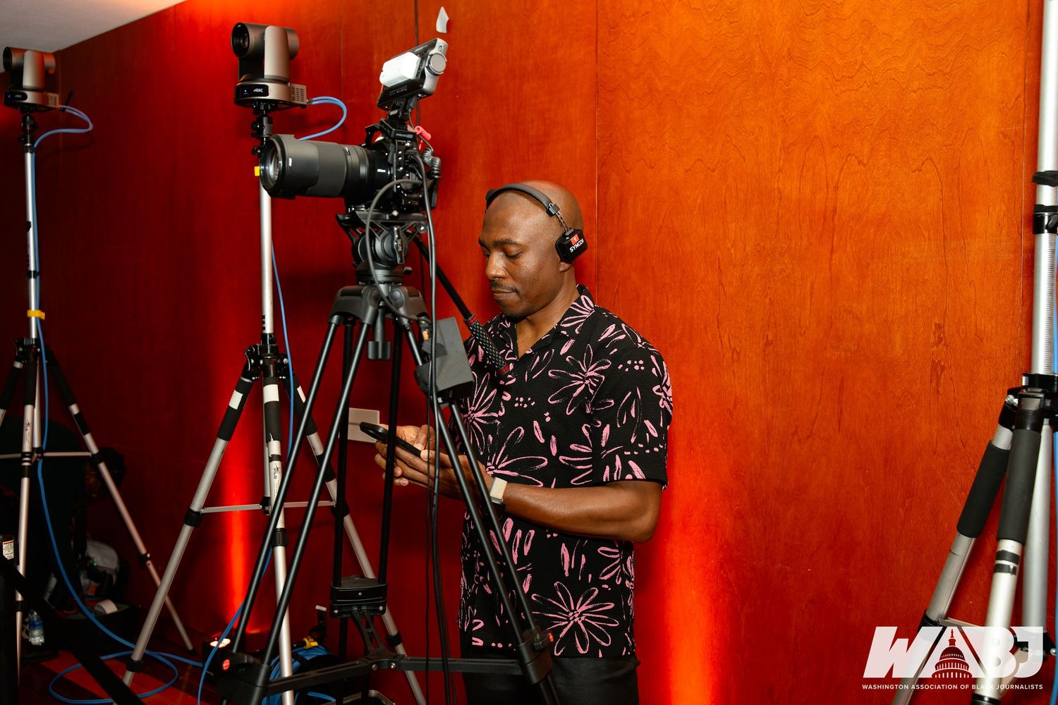 Professional video production setup with cameras and equipment against a red backdrop.