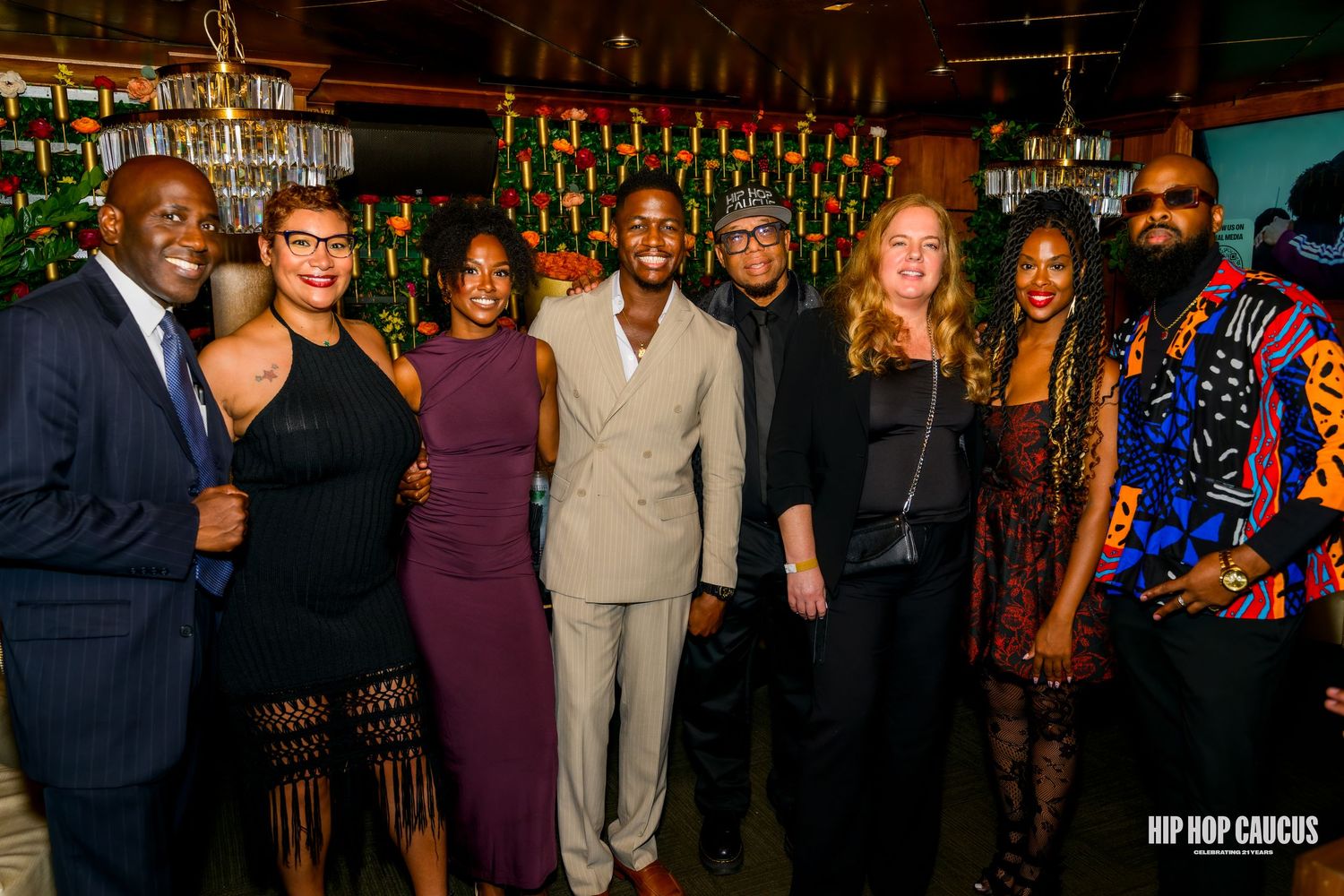 A group of people socializing and mingling at an evening event in a dimly lit venue.