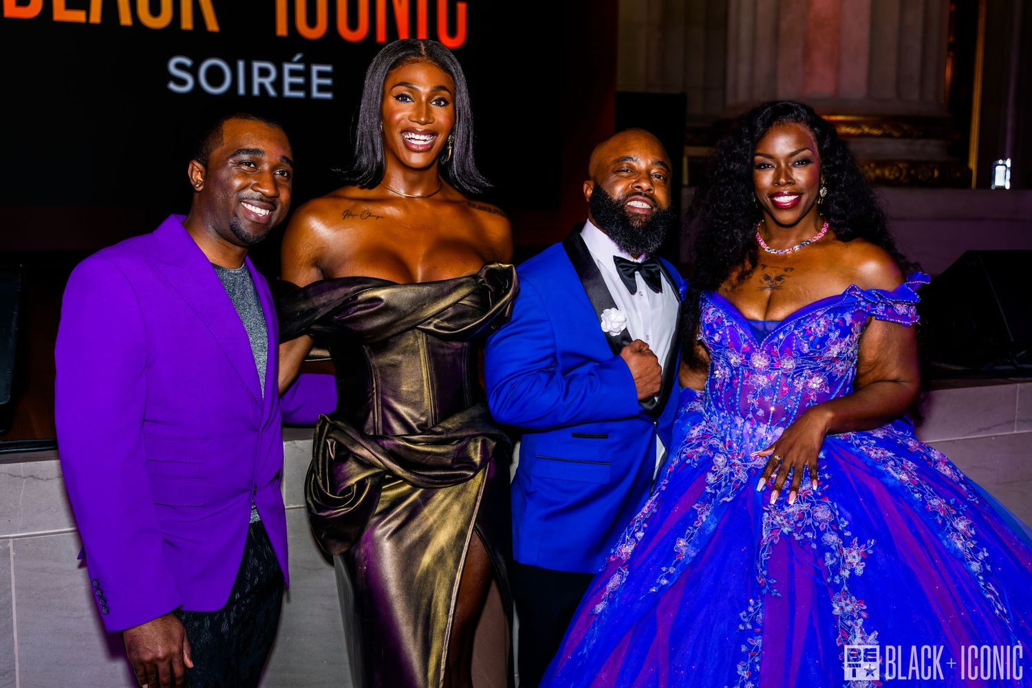 People in formal attire including blue and purple dresses celebrate at an elegant evening event.