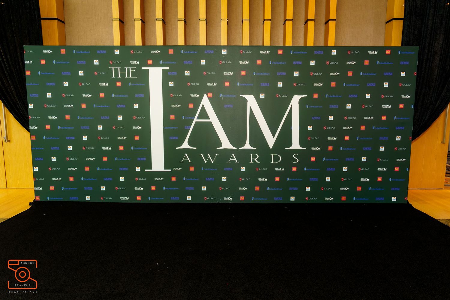 Yellow-colored promotional signs displaying text illuminate a dark backdrop with green patterned wall at an event space.