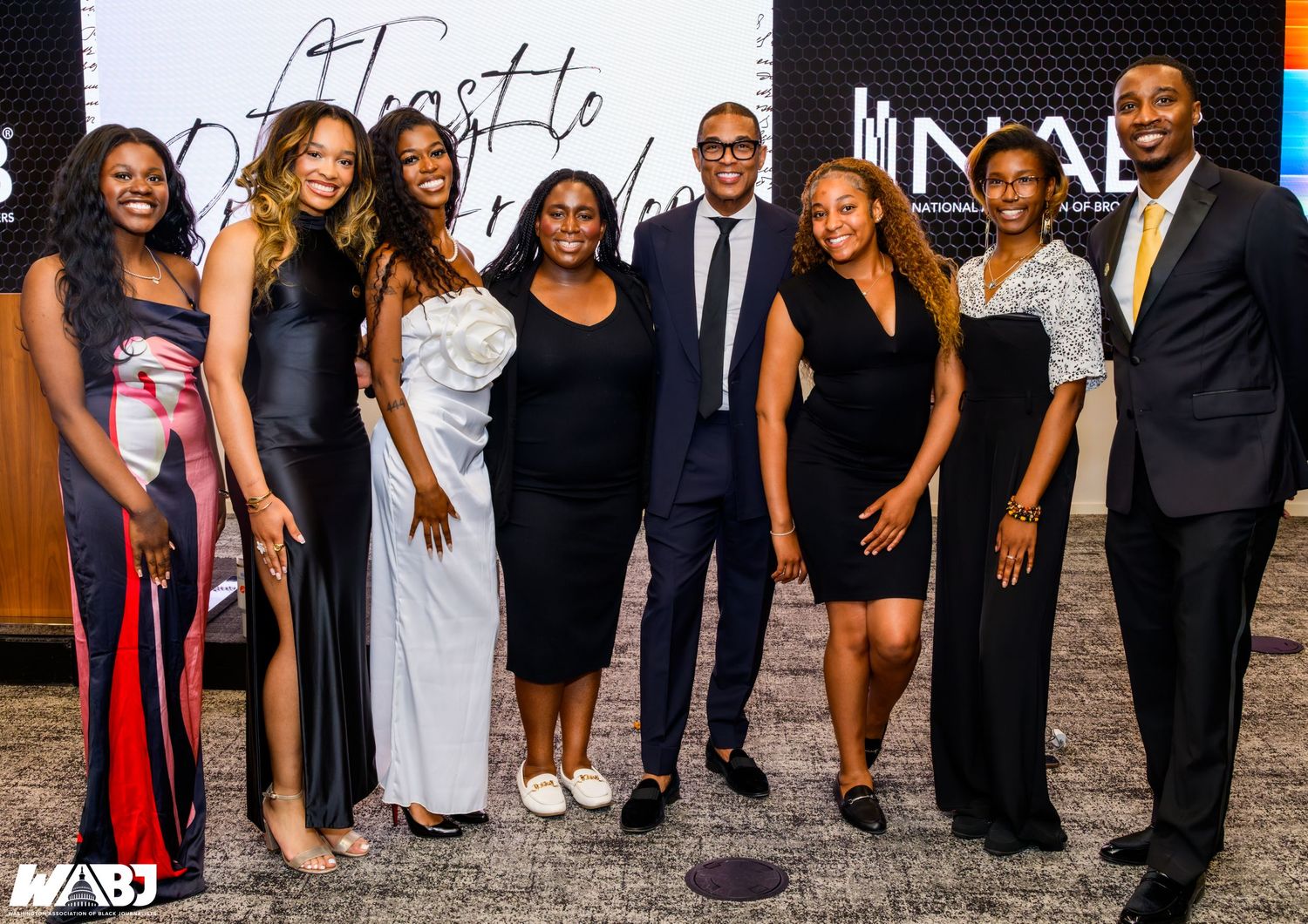 Group of eight professionals posing together at a formal NABO event, dressed in elegant attire.