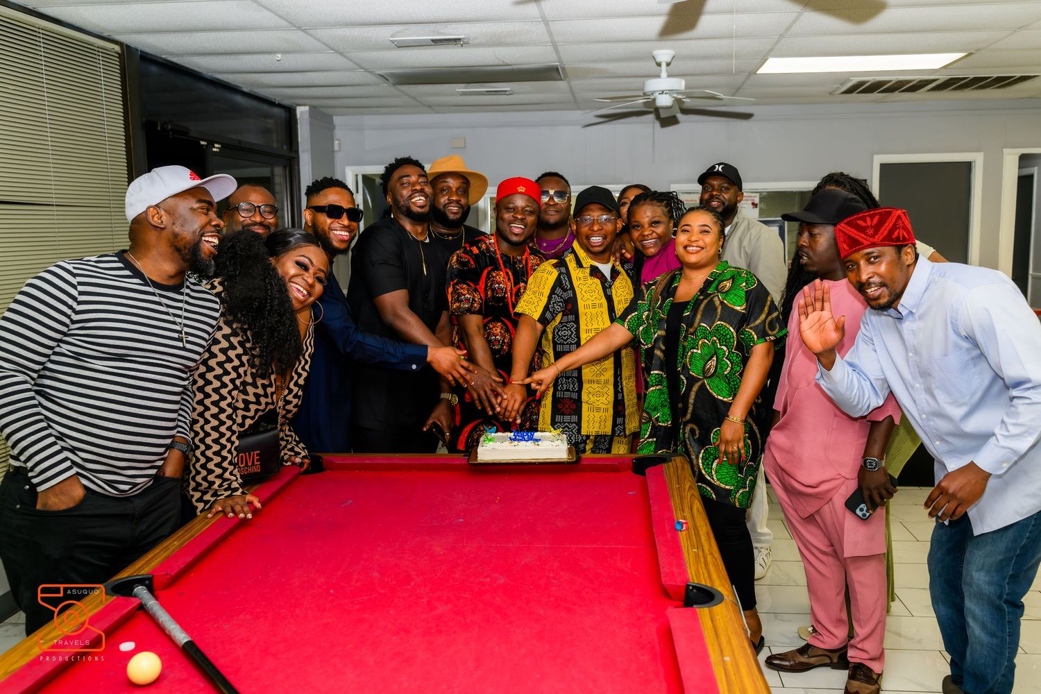 A panoramic view of people gathered around a red pool table during what appears to be a social event or party.