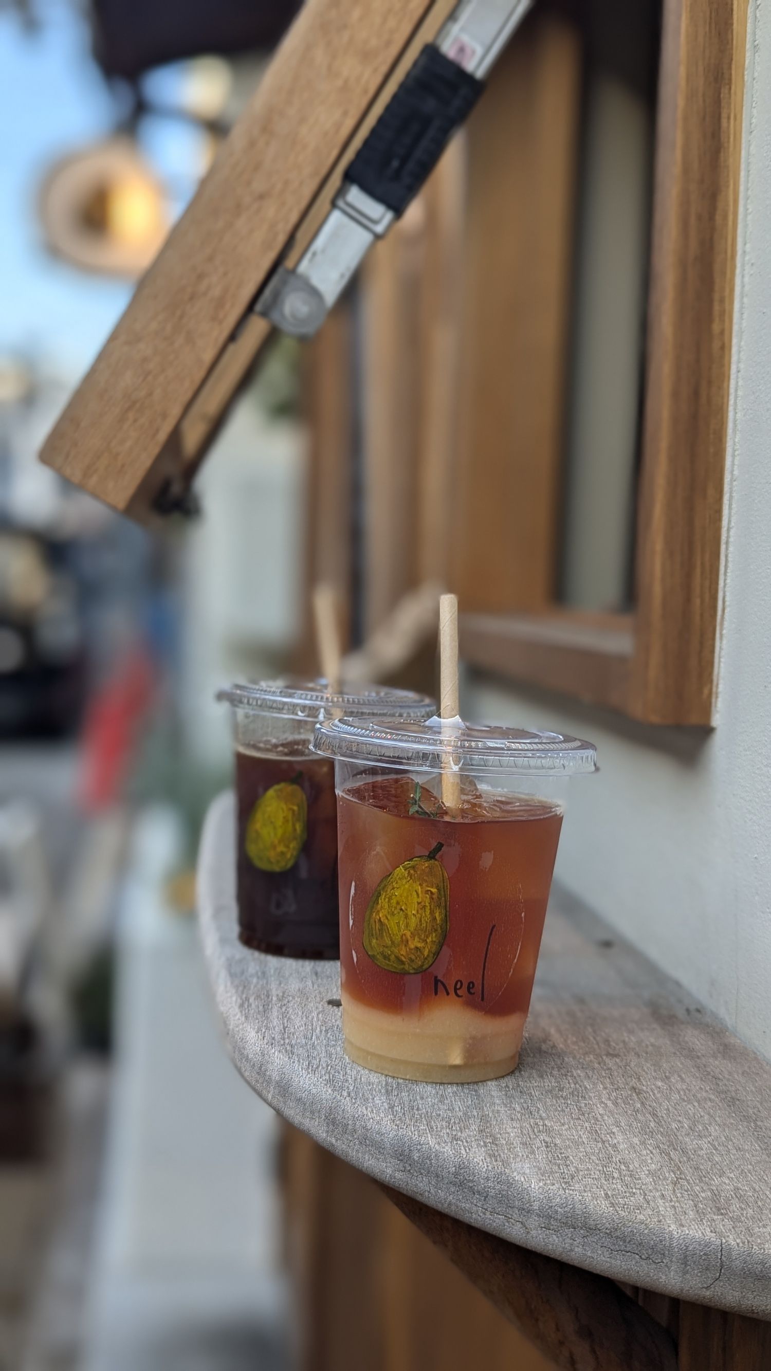 A lineup of cocktail glasses on a bar counter containing colorful drinks with citrus garnishes and custom coasters.