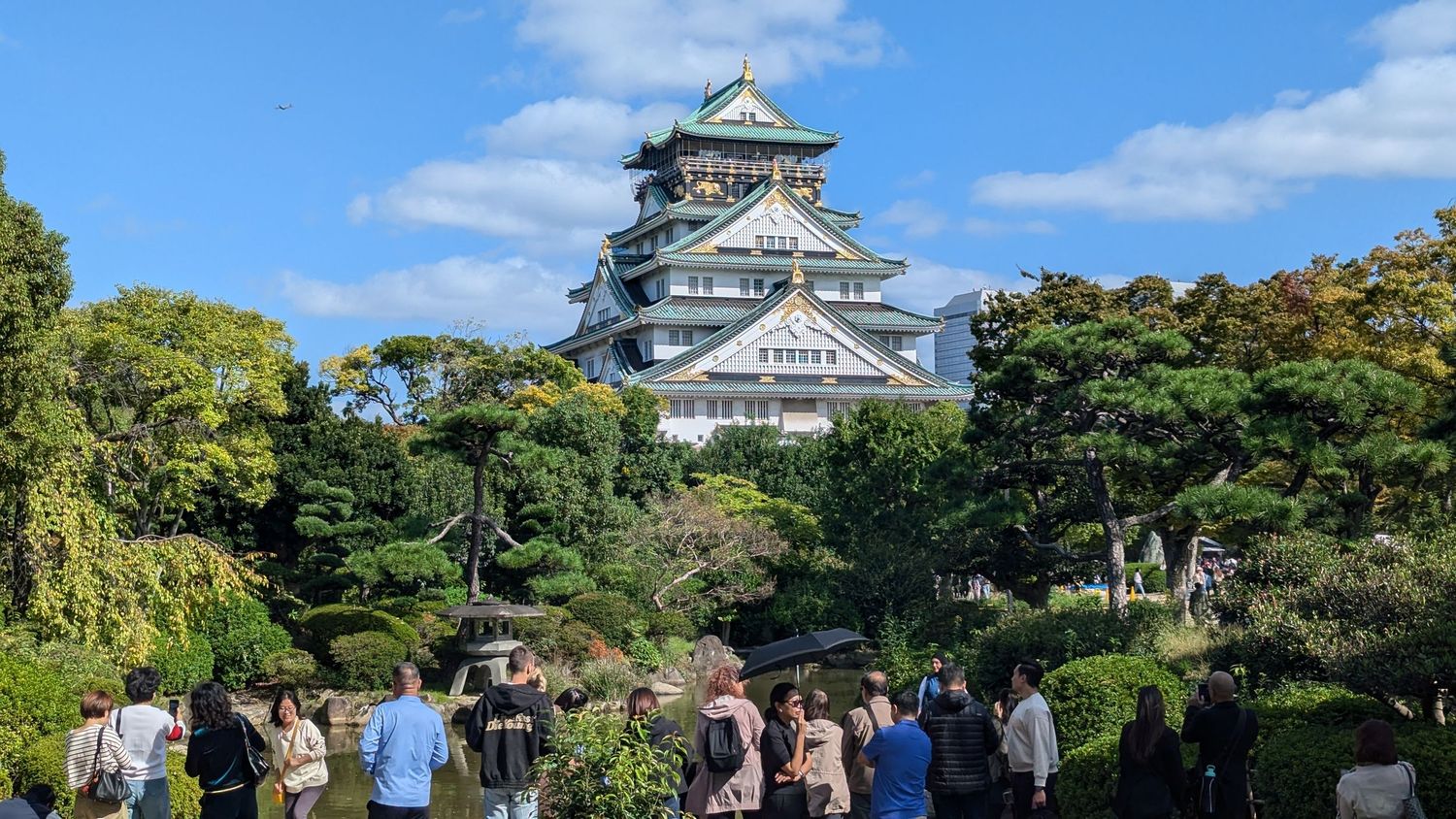A panoramic collage of Osaka Castle and its grounds featuring traditional Japanese architecture against blue skies.