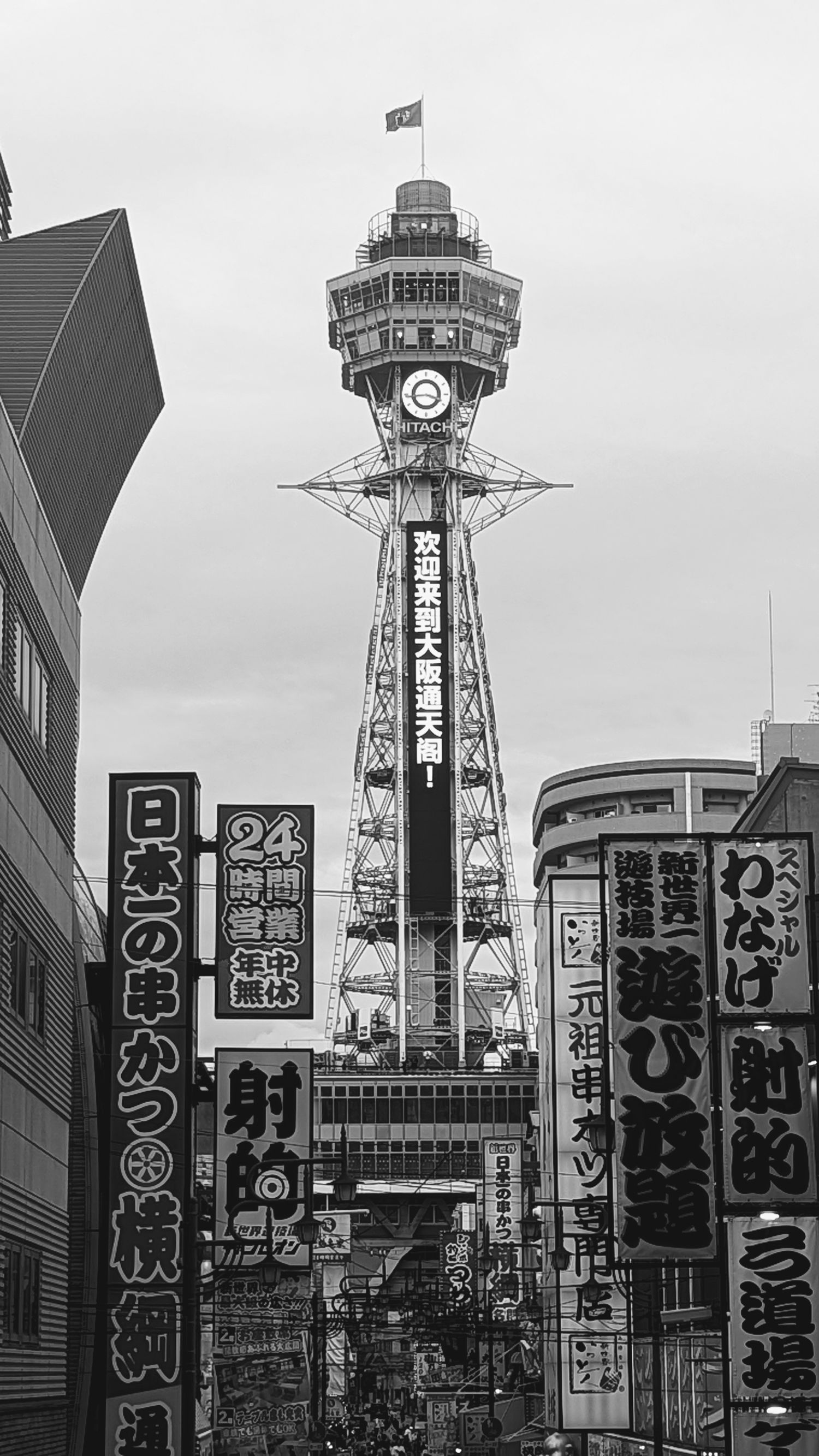 Historical black and white photo of the iconic Tsutenkaku Tower in Osaka's Shinsekai district surrounded by Japanese signage.