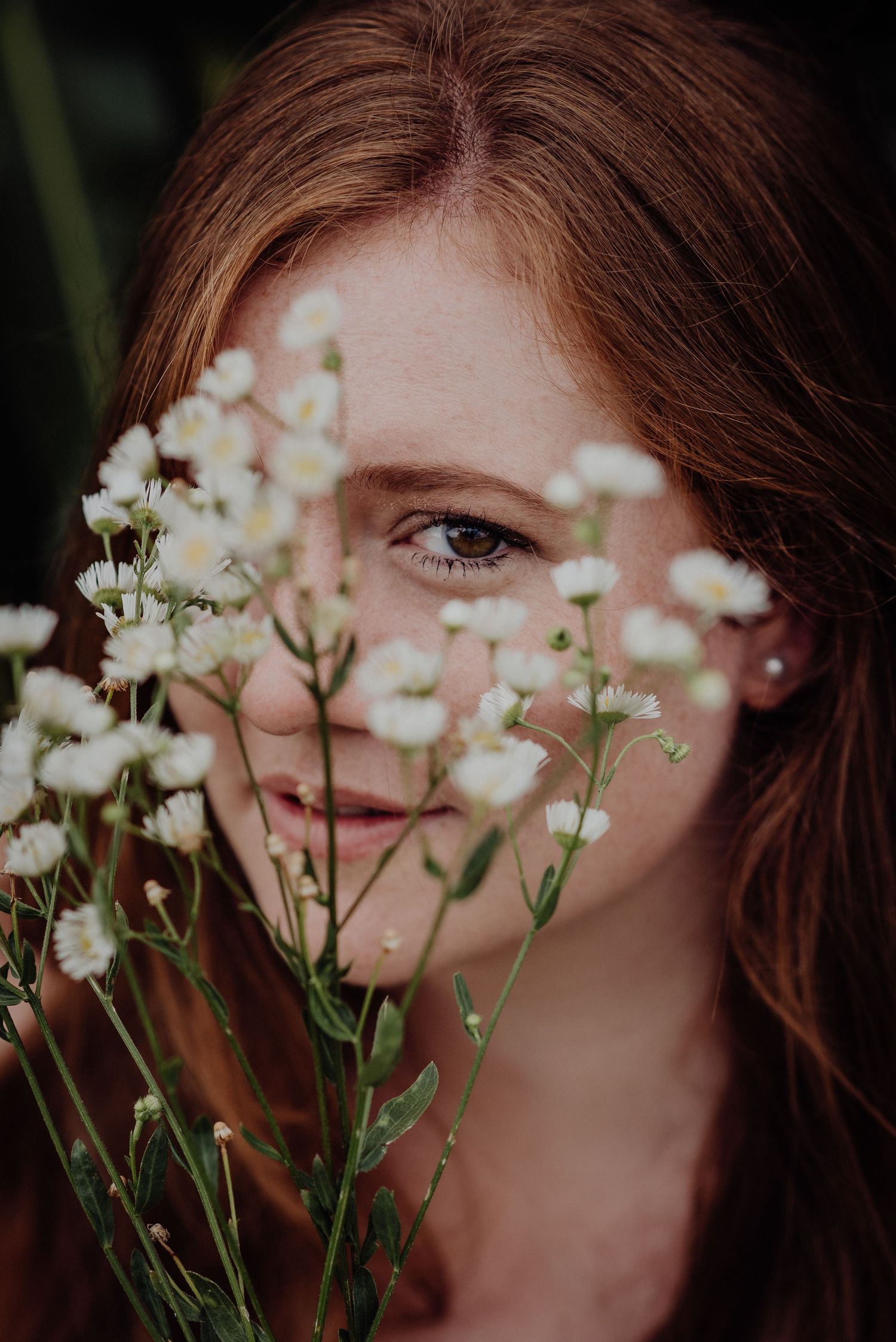 Rothaarige Frau blickt durch zarte weisse Blüten, natürliches Portrait mit Blumen im Vordergrund, aufgenommen in Thun.