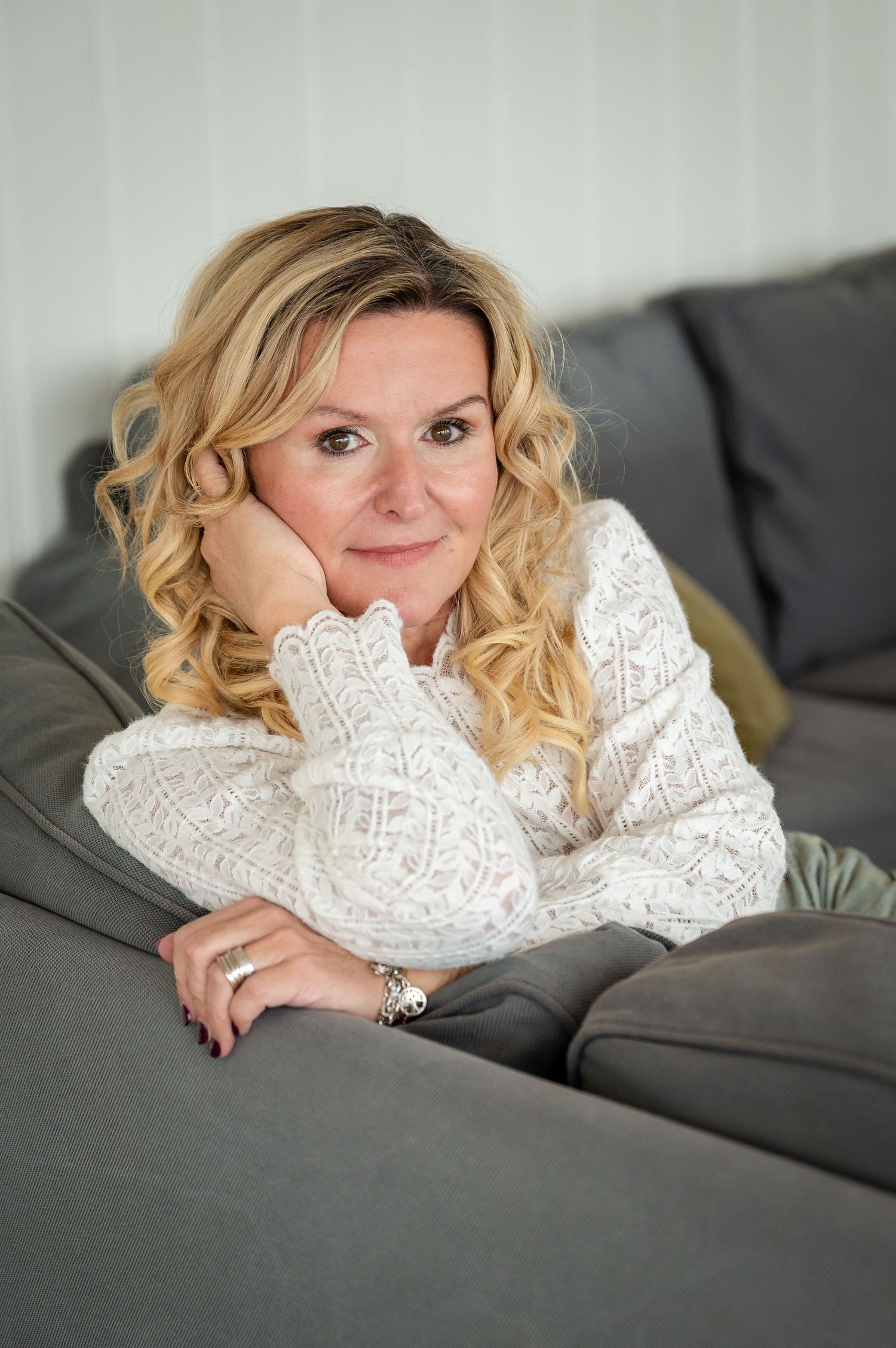 Selbstliebe-Portrait einer Frau auf dem Sofa, in weissem Spitzenoberteil, ruhig und präsent – fotografiert bei Thun, Bern.