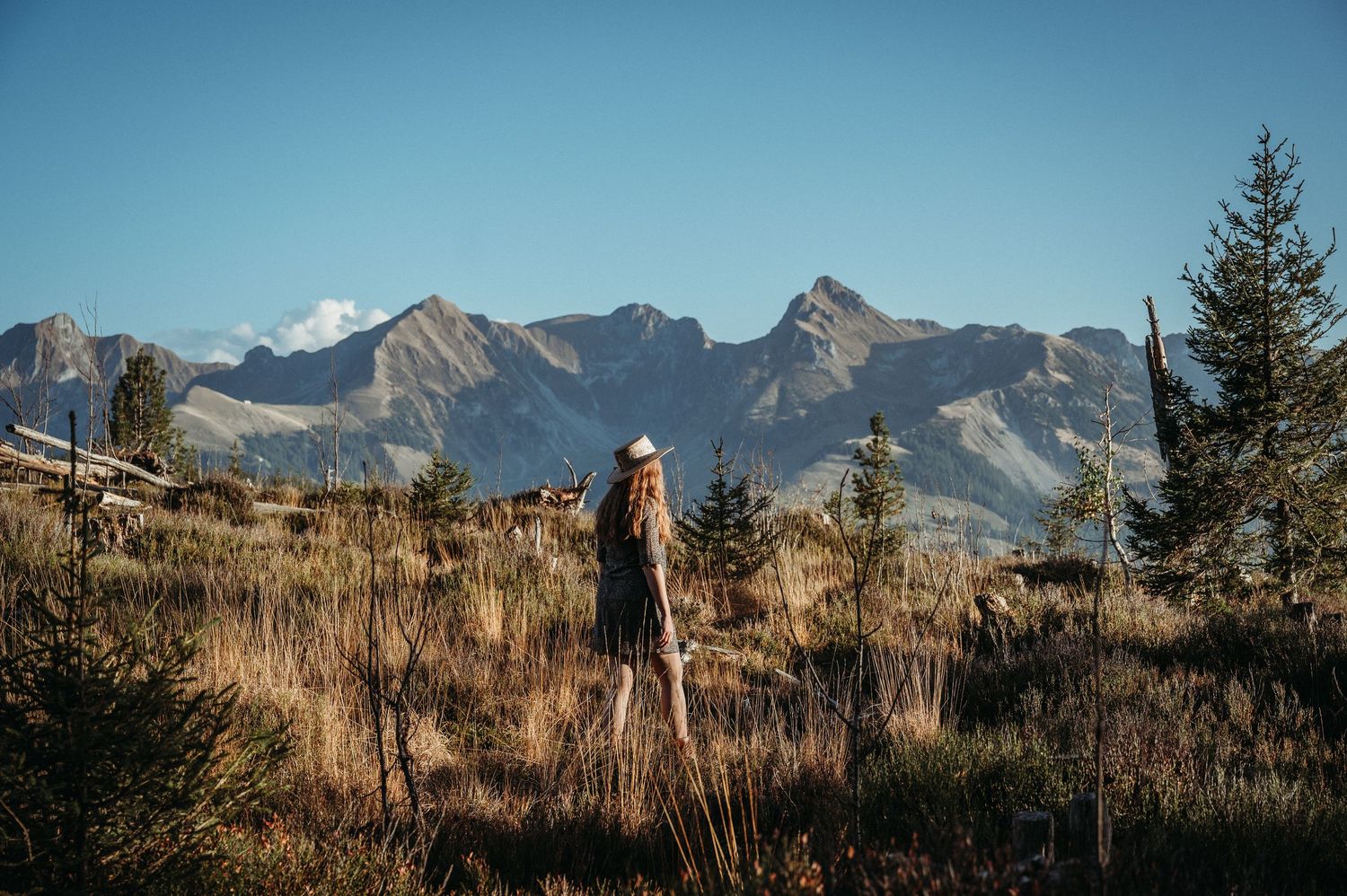 Frau mit Hut blickt in die Ferne vor beeindruckender Bergkulisse im Gantrischgebiet – Naturporträt mit Weitblick und Abendlicht.