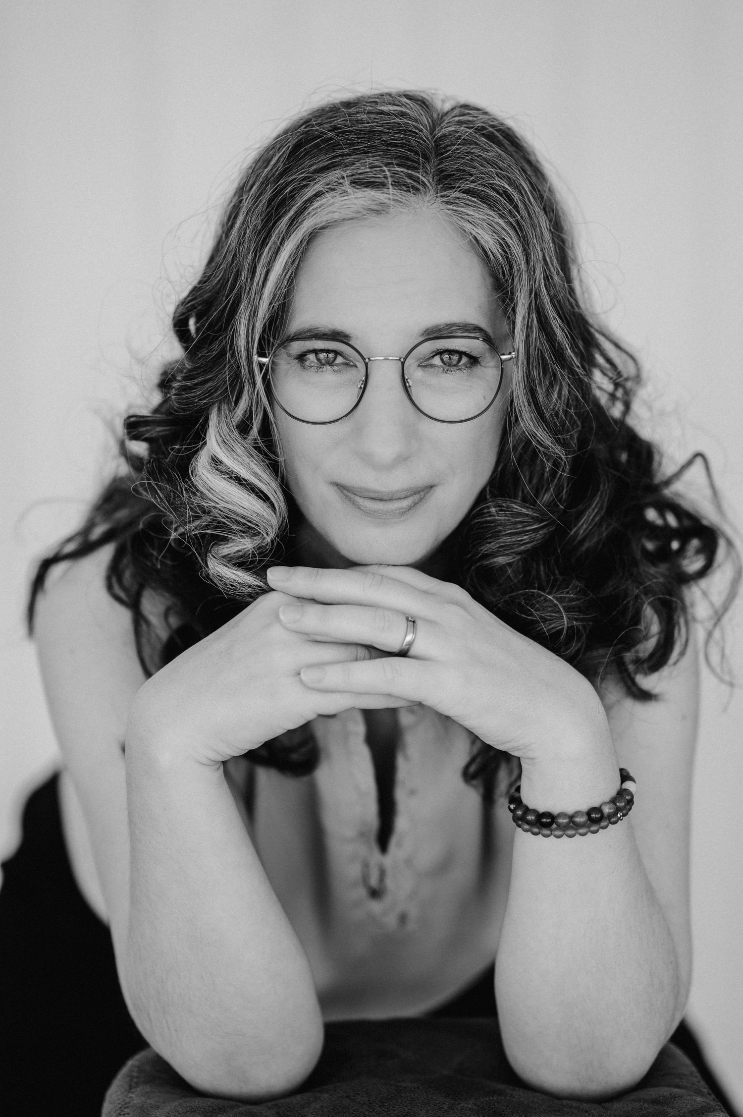 Selbstliebe-Portrait in Schwarz-Weiss – Frau mit Brille und Locken blickt ruhig in die Kamera, aufgenommen bei Thun