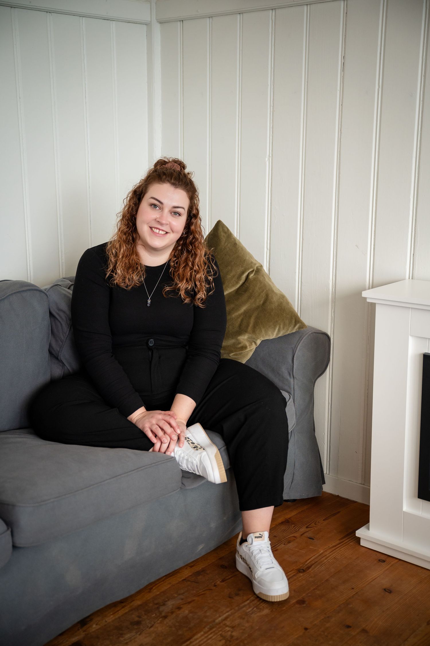 Frau im schwarzen Oberteil relaxed auf dem Sofa – Businessfoto für Coaching, Beratung oder kreative Dienstleistung