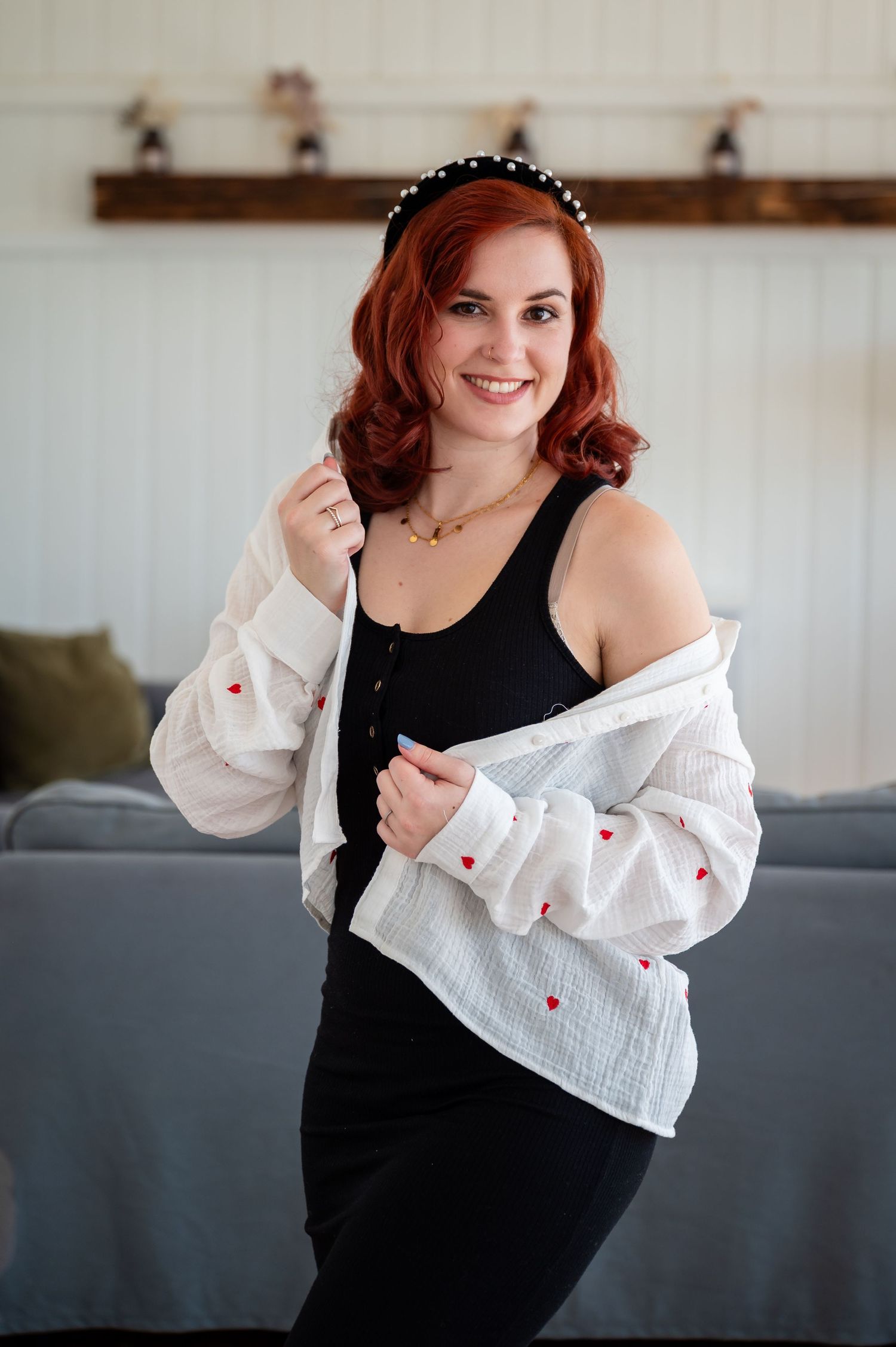 Junge Frau mit rotem Haar und schwarzem Kleid lächelt selbstbewusst in die Kamera – Selbstliebe-Shooting in entspannter, moderner Atmosphäre