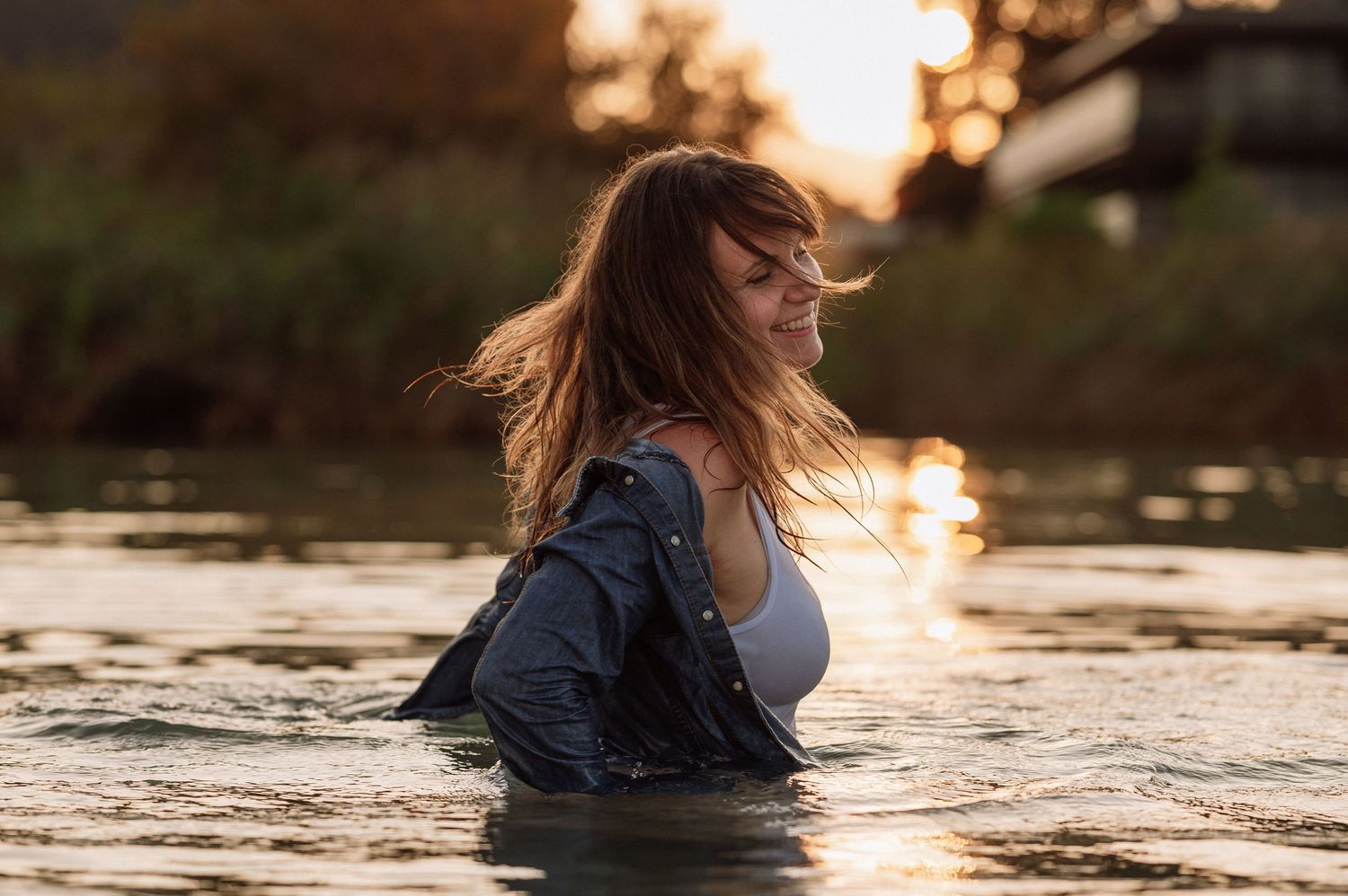 Boudoir-Shooting bei Sonnenuntergang: lachende Frau in nasser Kleidung im See, sinnlich, frei und lebensfroh im Abendlicht.