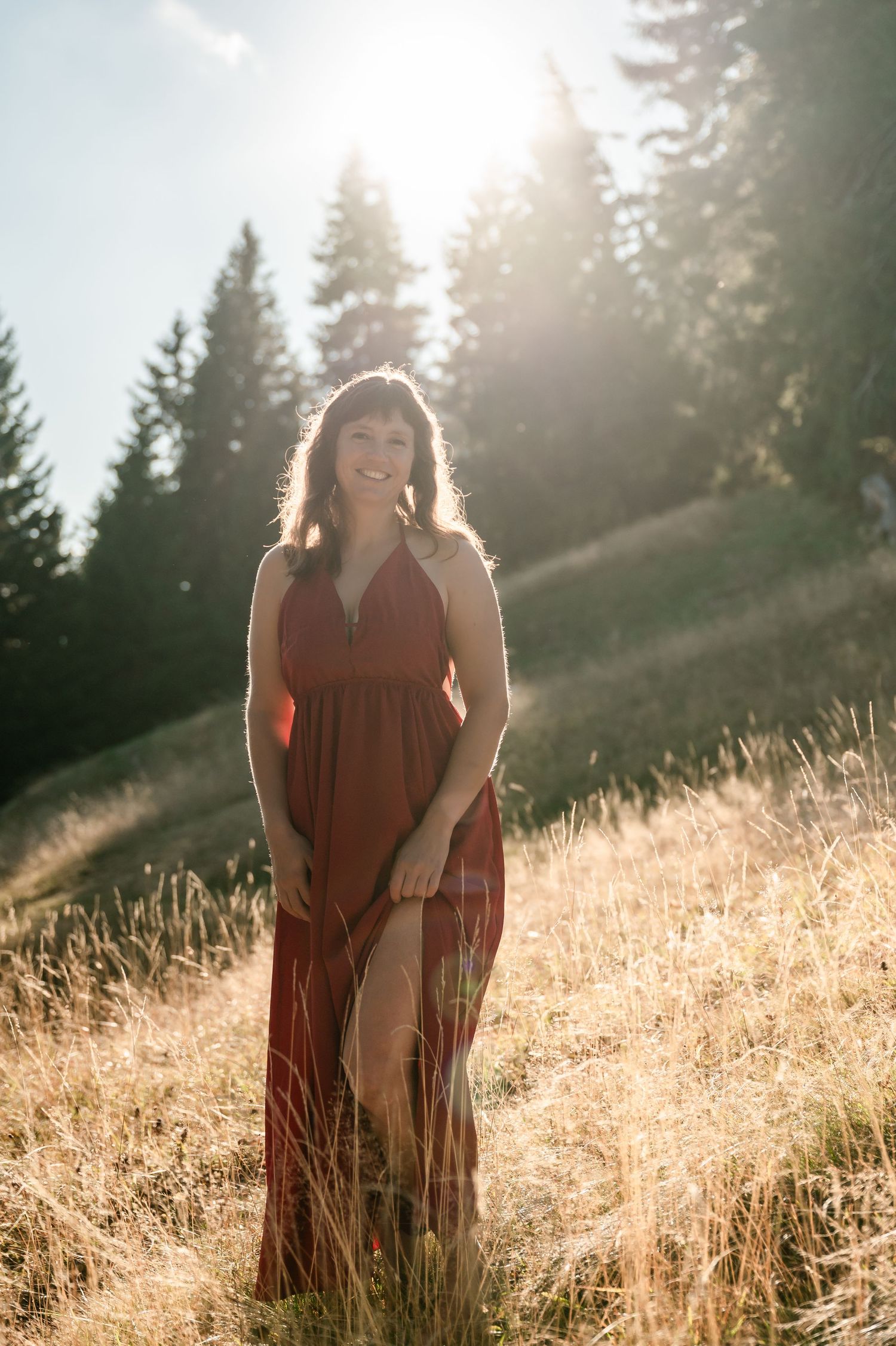 Frau in rotem Kleid im Wald bei Thun, mit Blick auf das Berner Oberland im Abendlicht