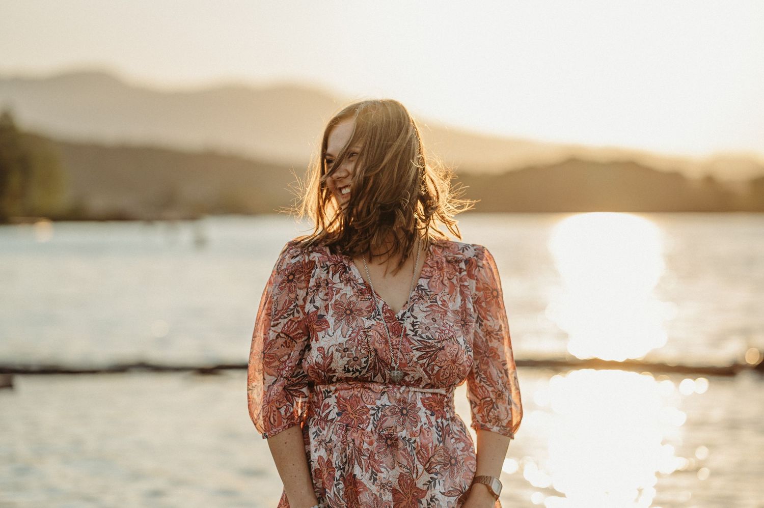 Selbstliebe-Fotoshooting am See bei Sonnenuntergang – Frau in floraler Kleidung strahlt Ruhe und Freude aus