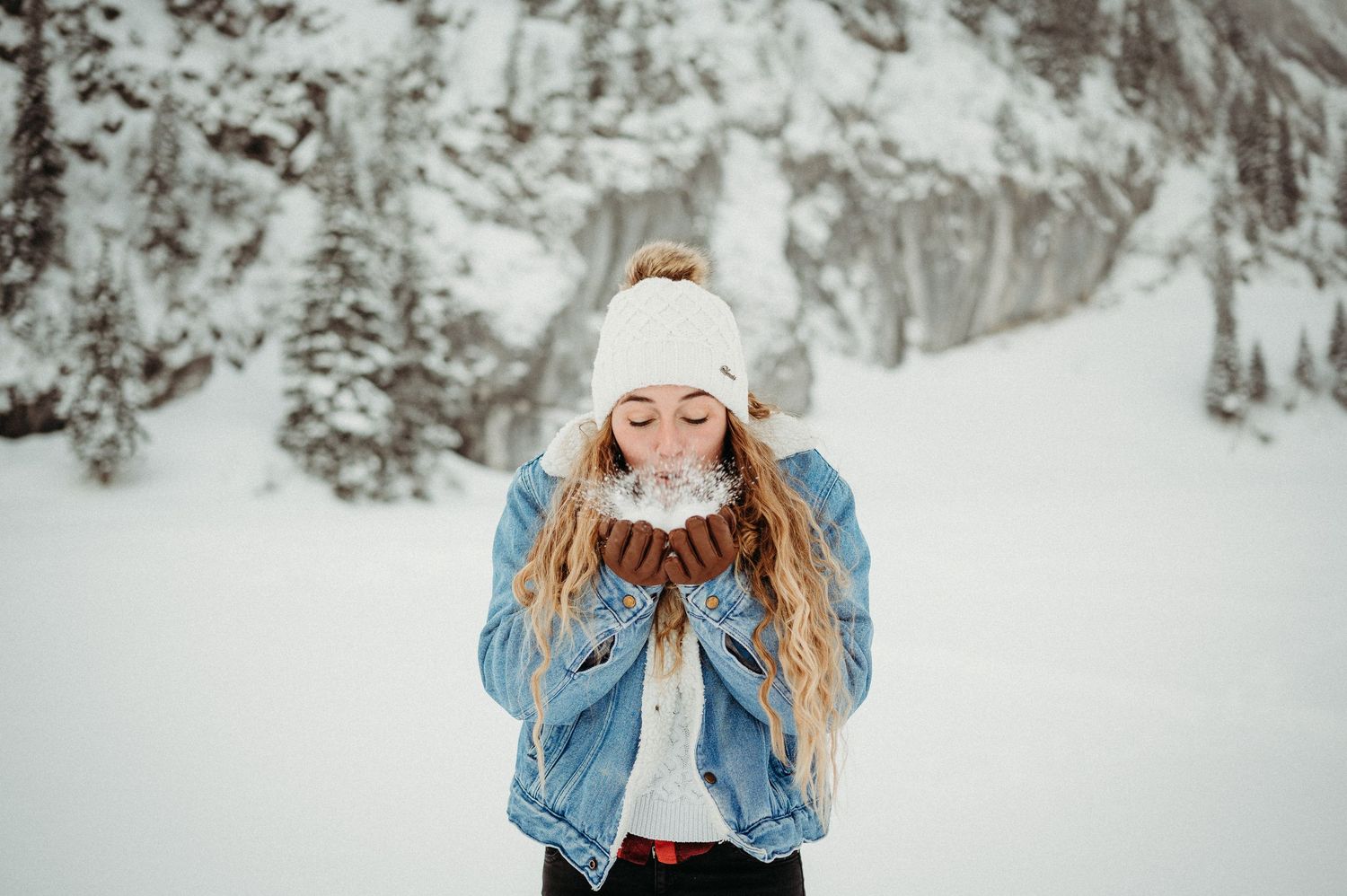 Frau mit Mütze im tief verschneiten Winterwald im Berner Oberland. Portraitshooting in der Natur mit Weitblick und Winterzauber.
