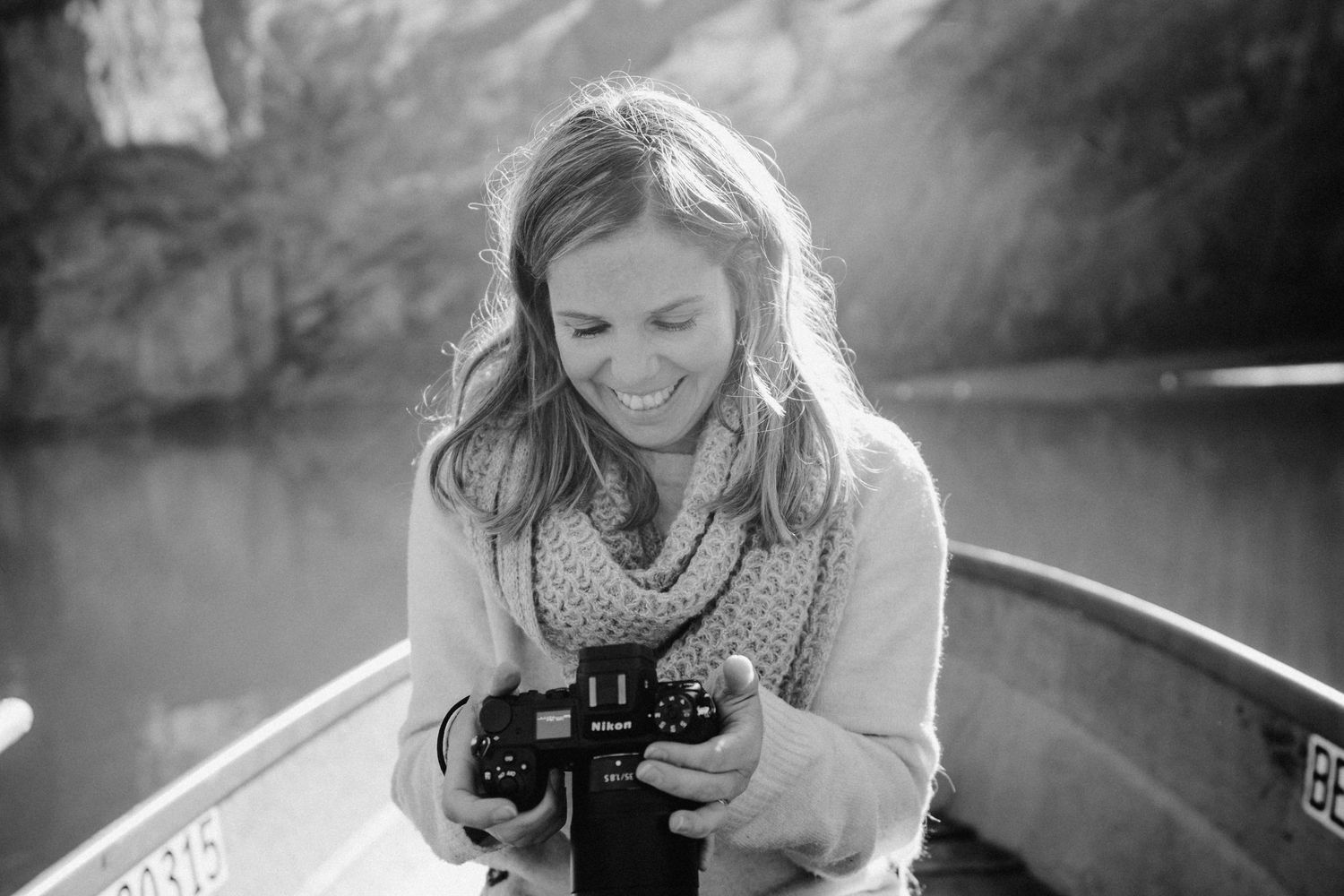 Frauen-Fotografin mit Kamera auf einem Boot am Oeschinensee im Morgenlicht