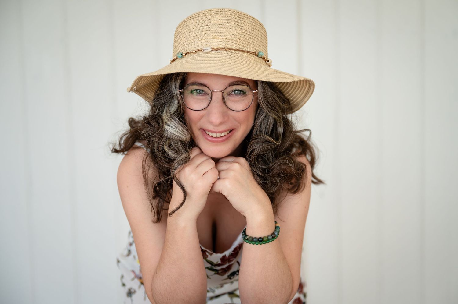 Fröhliche Frau mit Strohhut und Brille lächelt in die Kamera – sommerlich, natürlich und voller Lebensfreude.