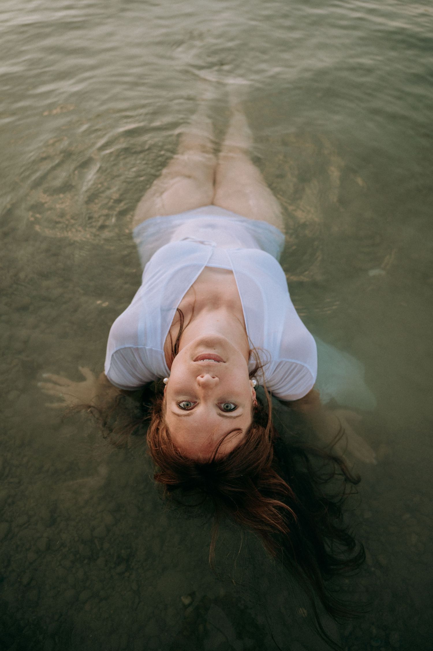 Boudoir-Shooting im Thunersee: Frau lehnt sich entspannt im Wasser zurück, nasses Shirt, geschlossene Augen – sinnlich und frei.