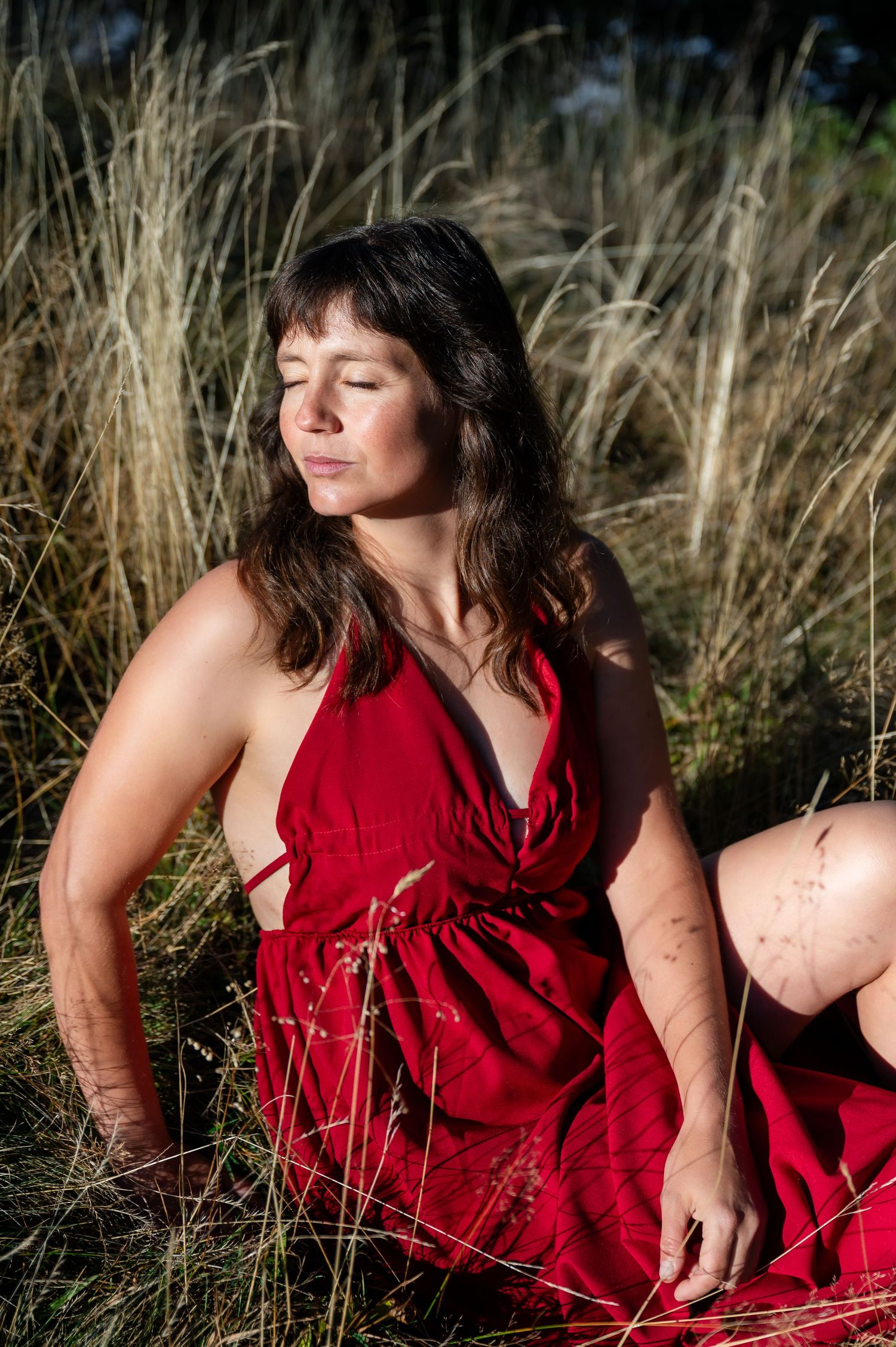 Sinnliches Boudoirfoto in der Natur nahe Thun – Frau im roten Kleid in goldenem Licht.