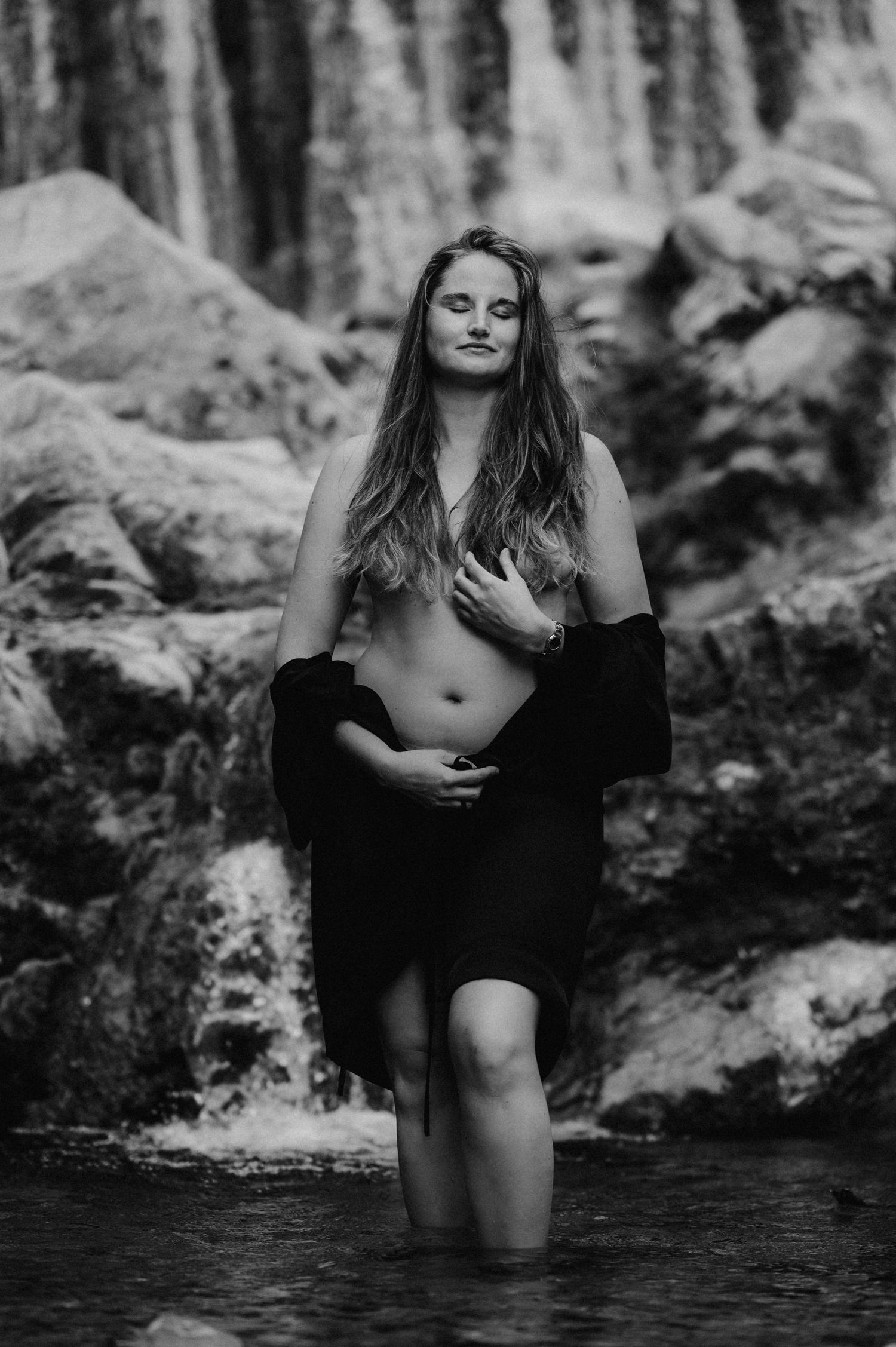 Selbstbewusste Frau im Wasser vor Wasserfall bei Thun – Boudoirfoto in Schwarz-Weiss, kraftvoll, natürlich und voller Präsenz.