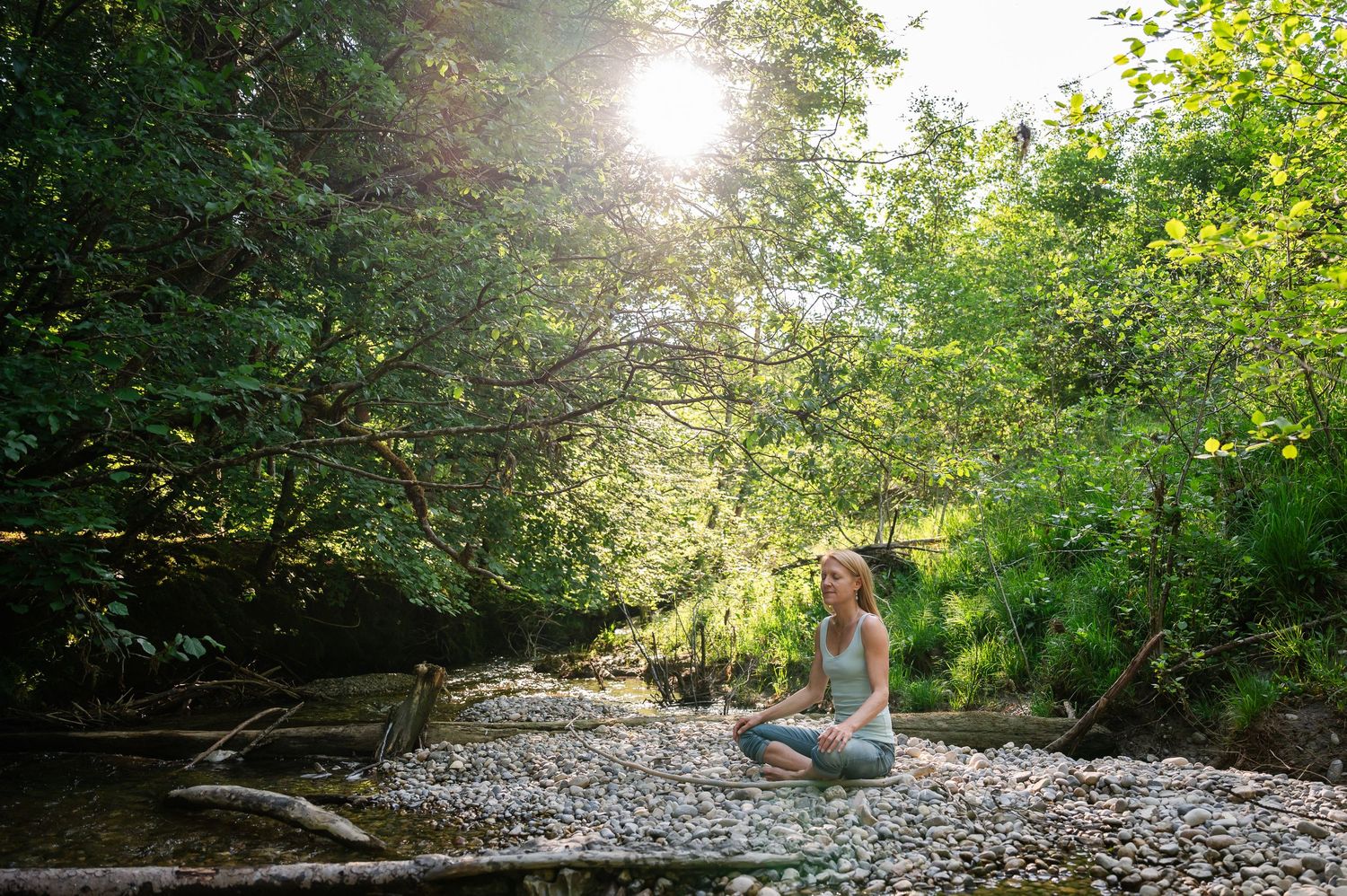Frau meditiert am Waldbach bei Thun – friedlicher Moment voller Achtsamkeit und Naturverbundenheit