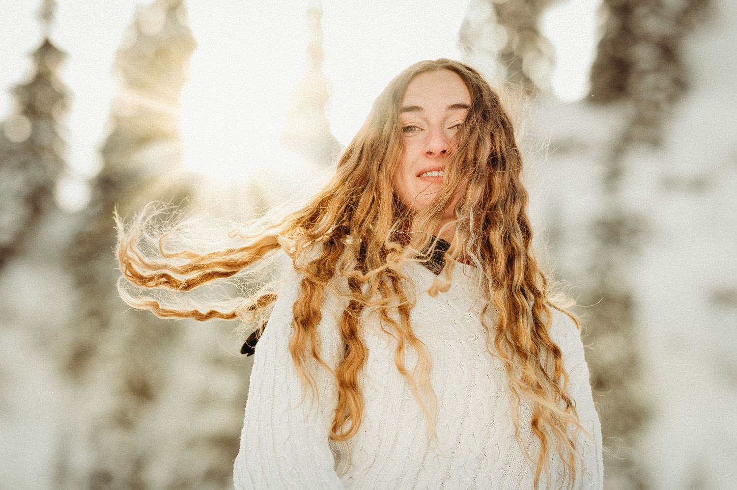 Porträt einer Frau mit wehenden Locken im Schnee. Winterliches Fotoshooting in der Natur rund um Thun – lebendig und wild.
