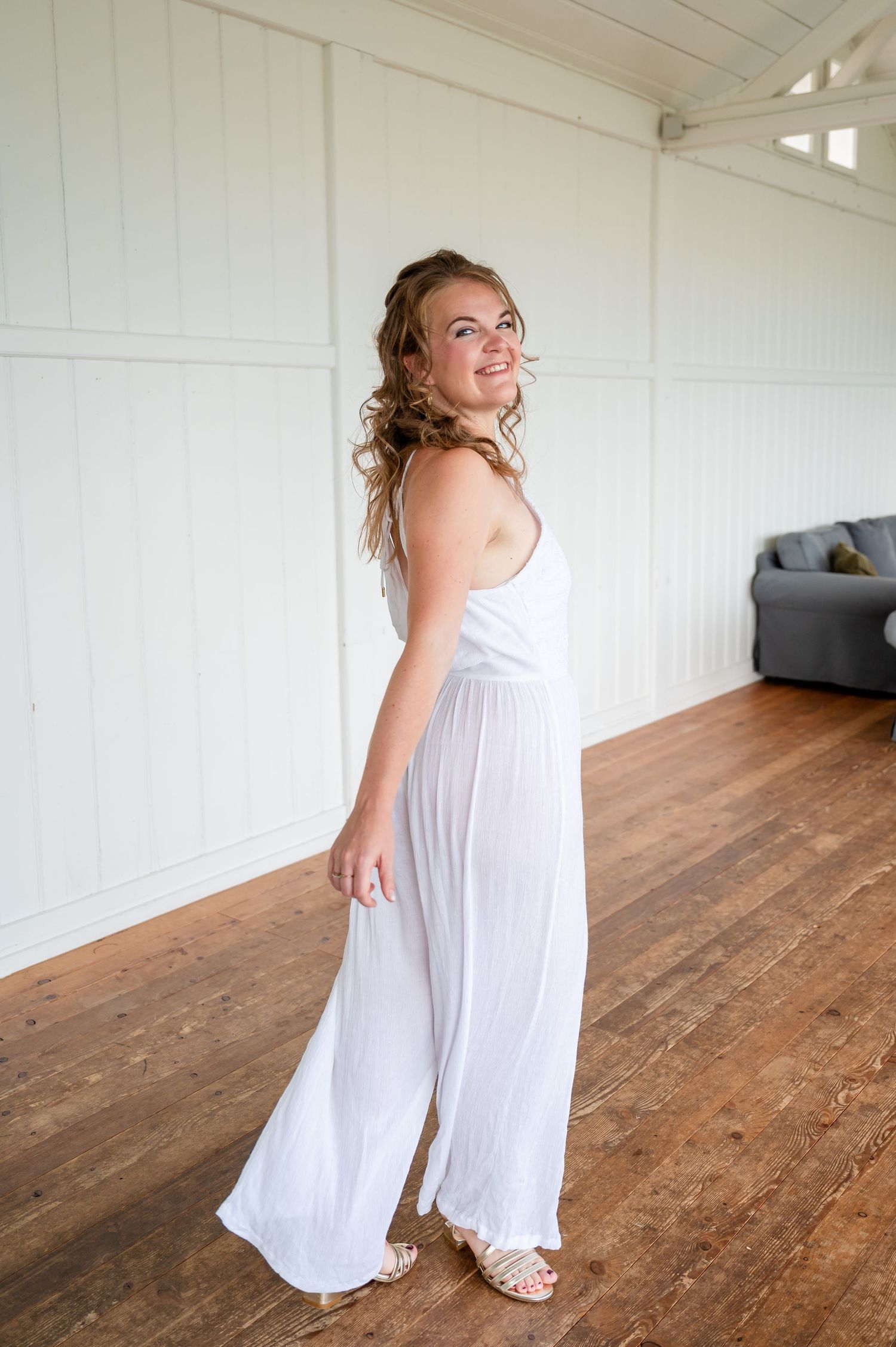 Selbstliebe-Shooting mit junger Frau im weißen Jumpsuit – natürliche Bewegung und Freude im lichtdurchfluteten Raum