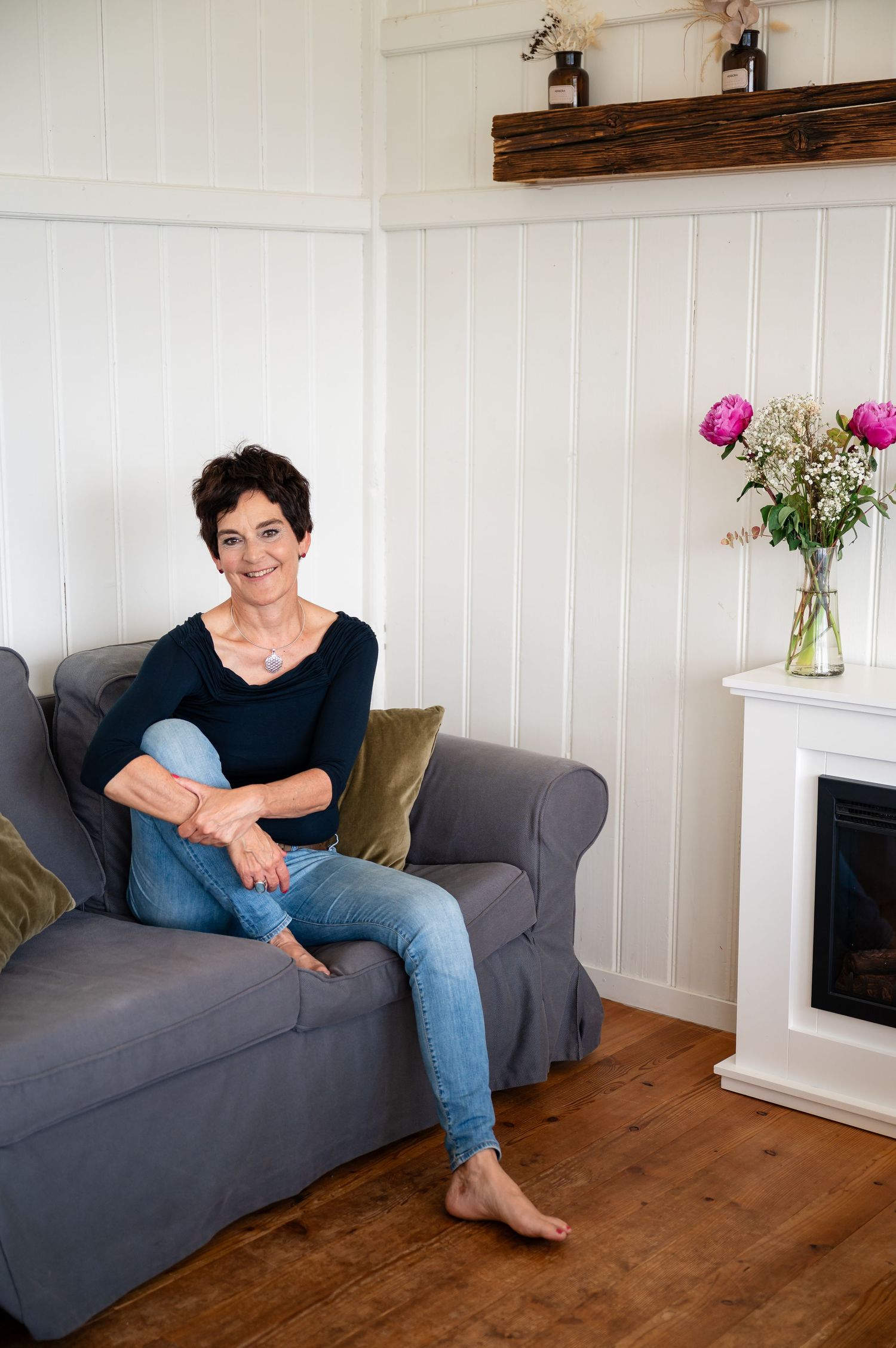 Frau in Jeans sitzt entspannt im Wohnzimmer-Setting – authentisches Coachingportrait aus der Region Thun