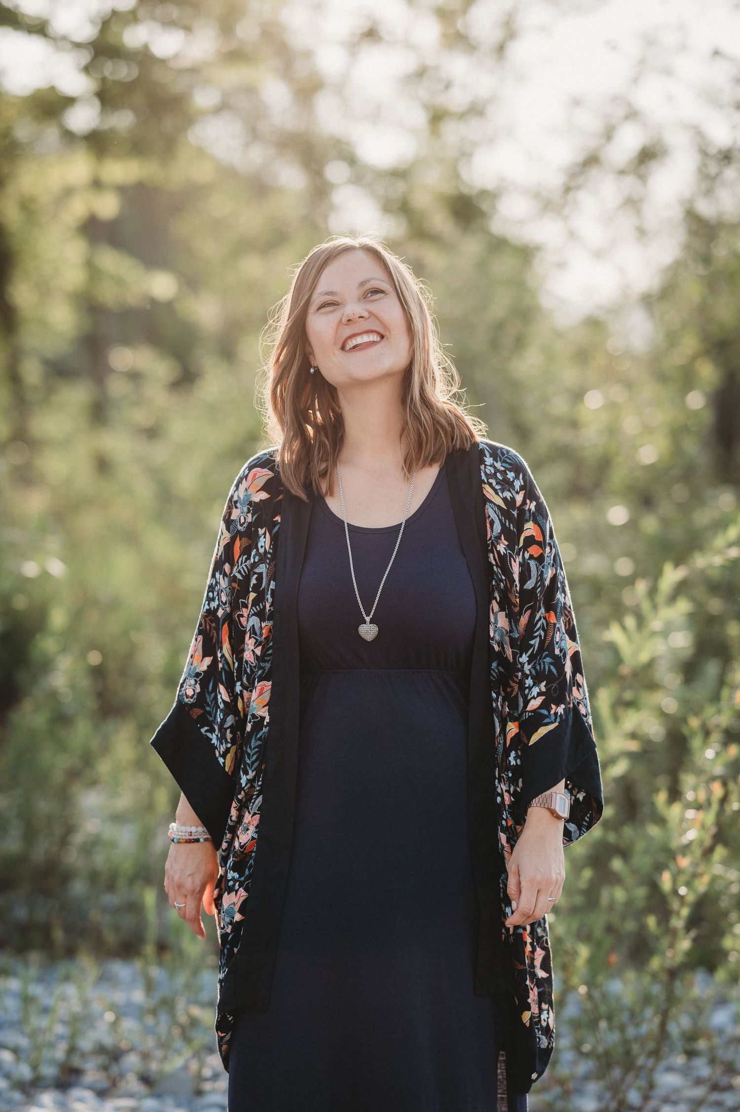 Frau mit mittellangem Haar im gemusterten KImono steht in der Natur bei Sonnenuntergang – Outdoor-Portrait