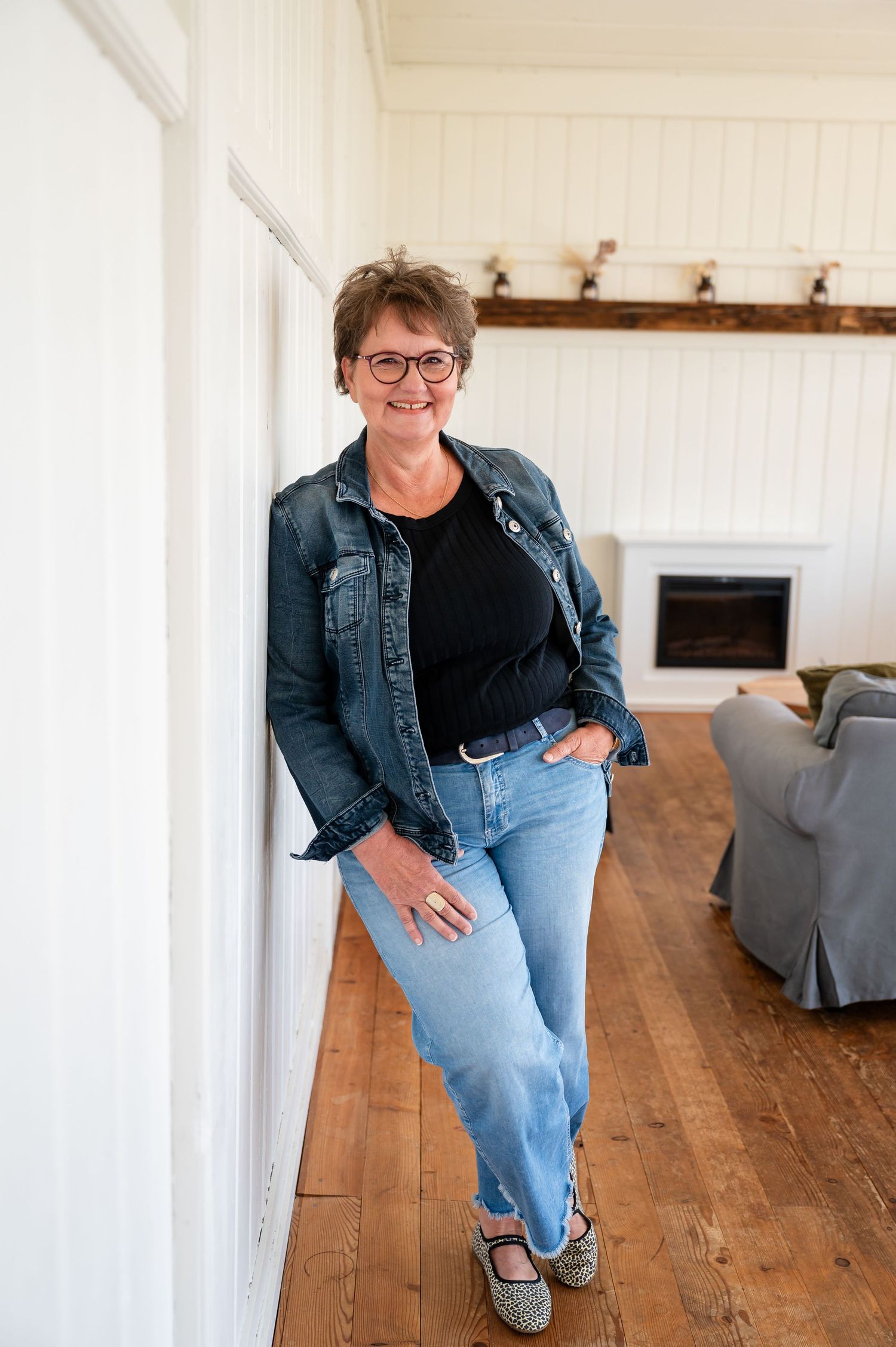 Selbstbewusste Frau lehnt lässig an der Wand, in Jeans und Jeansjacke – entspannte Atmosphäre beim Selbstliebe-Shooting in Thun.