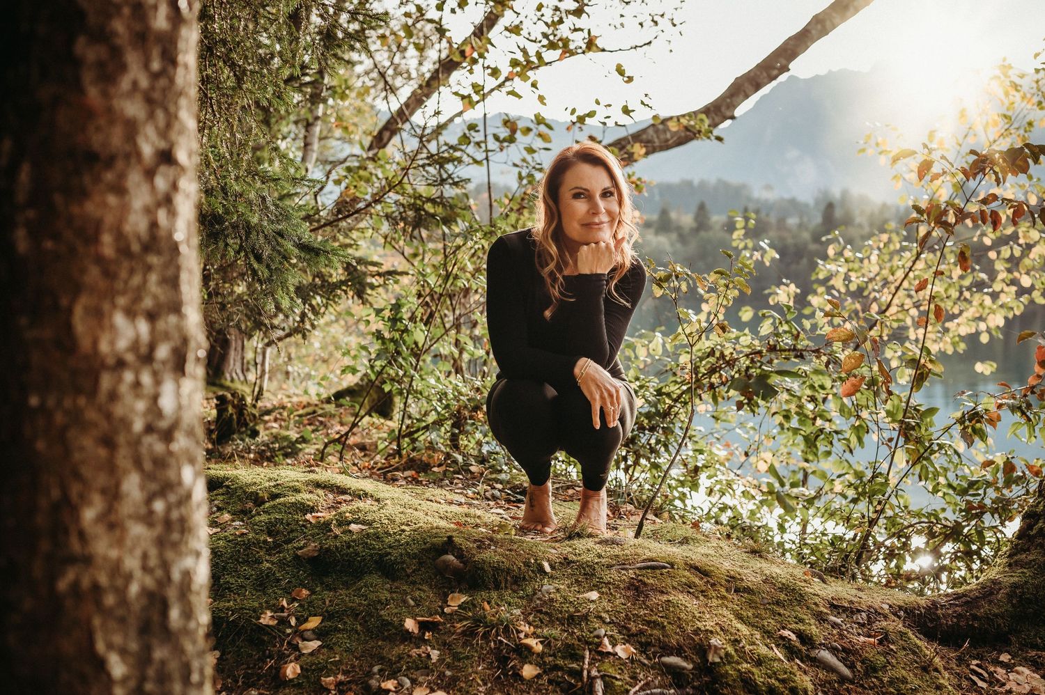 Authentisches Businessportrait einer Yogalehrerin in der Natur – Wald, See und Sonnenlicht im Hintergrund