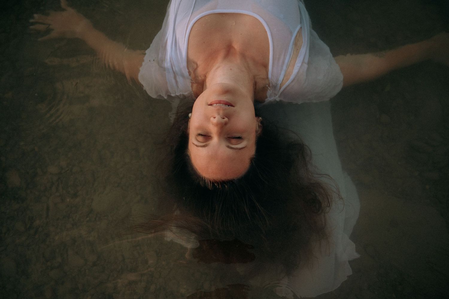 Boudoir-Shooting im Thunersee: Frau treibt in nassem Kleid im Wasser, Blick zur Kamera – sinnlich, ruhig, verwoben mit der Natur.
