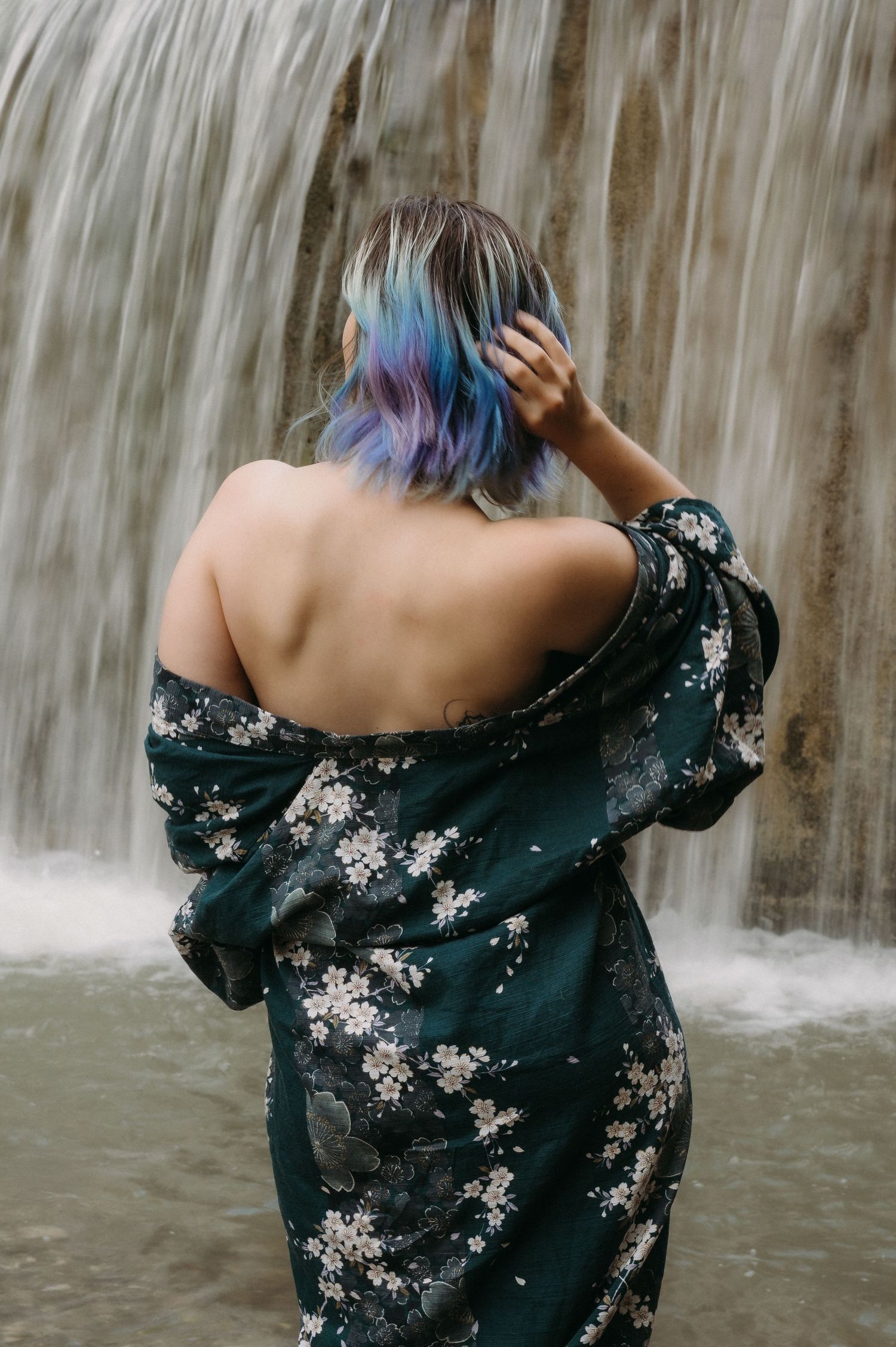 Frau mit bunten Haaren im Kimono vor Wasserfall an der Gürbe – sinnliches Boudoirbild mit Rückenansicht und Naturkulisse.