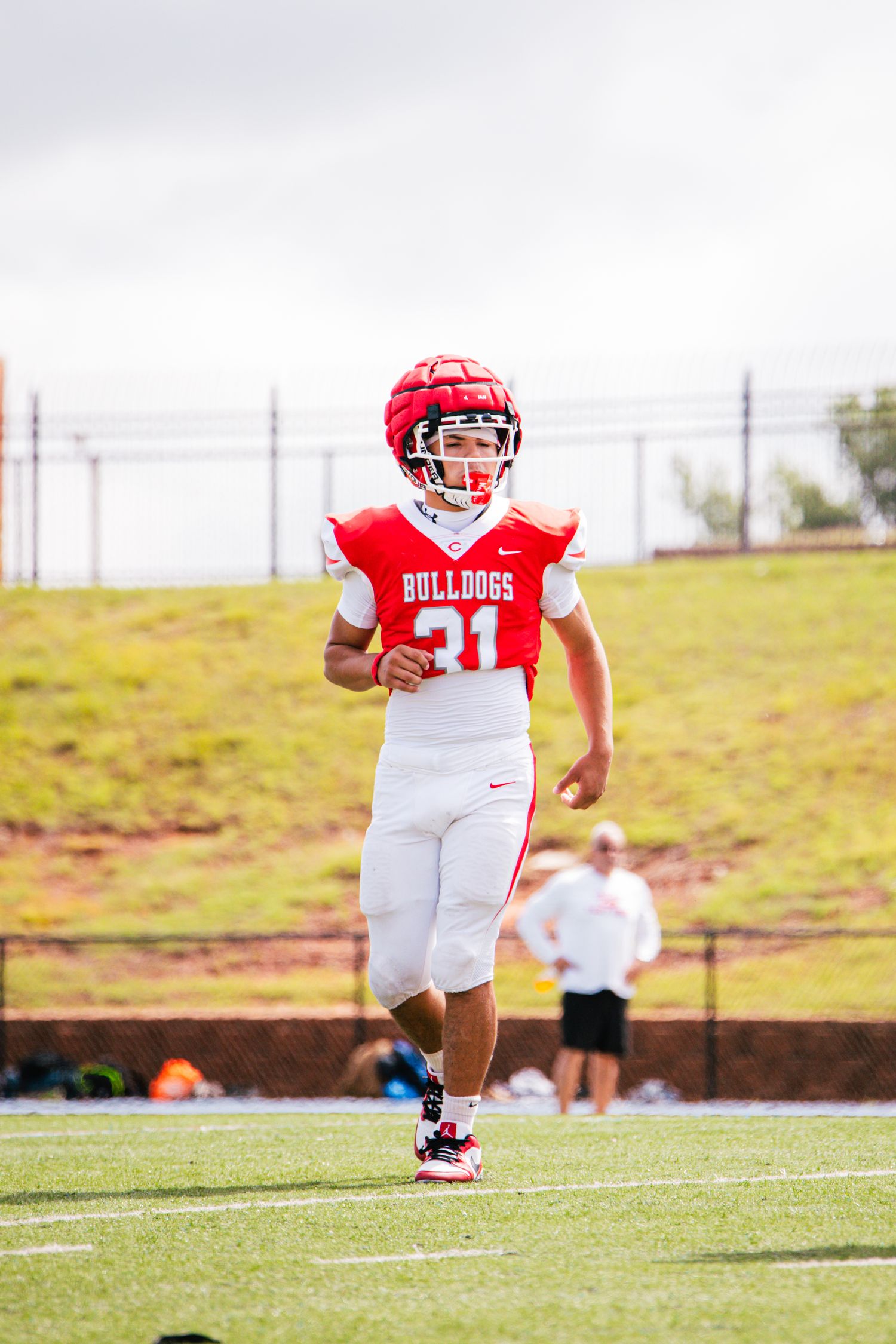 A Bulldogs football player wearing number 31 jogs across the field during a game.