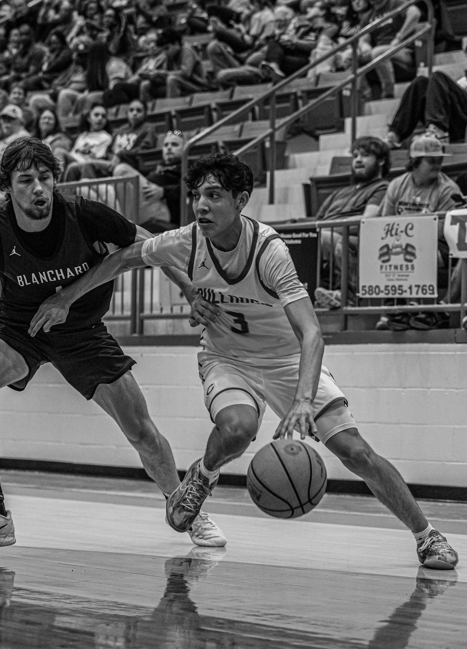 Black and white photo of basketball player number 3 driving past a Blanchard defender.