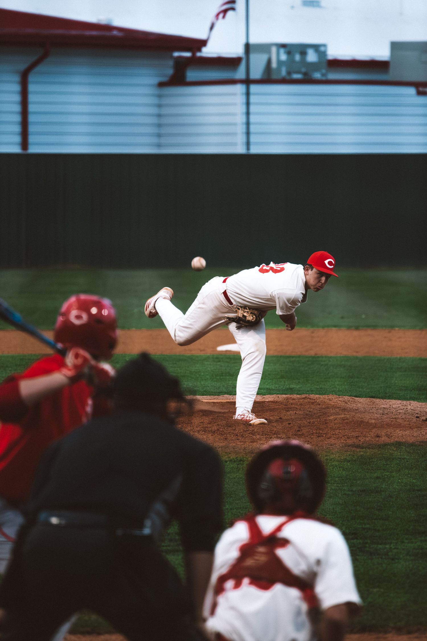 Baseball pitcher in white uniform delivers a pitch during a competitive night game.