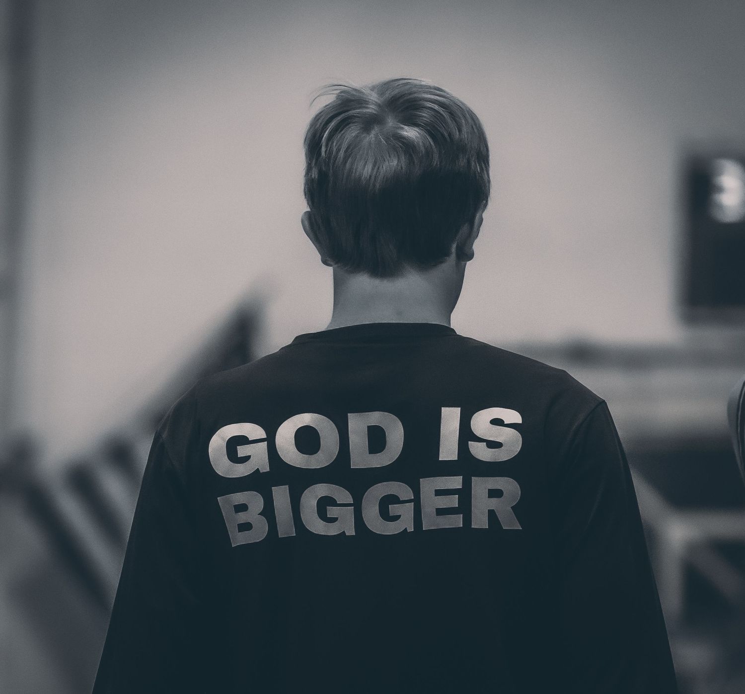 Person wearing a black shirt with God Is Bigger printed on the back.