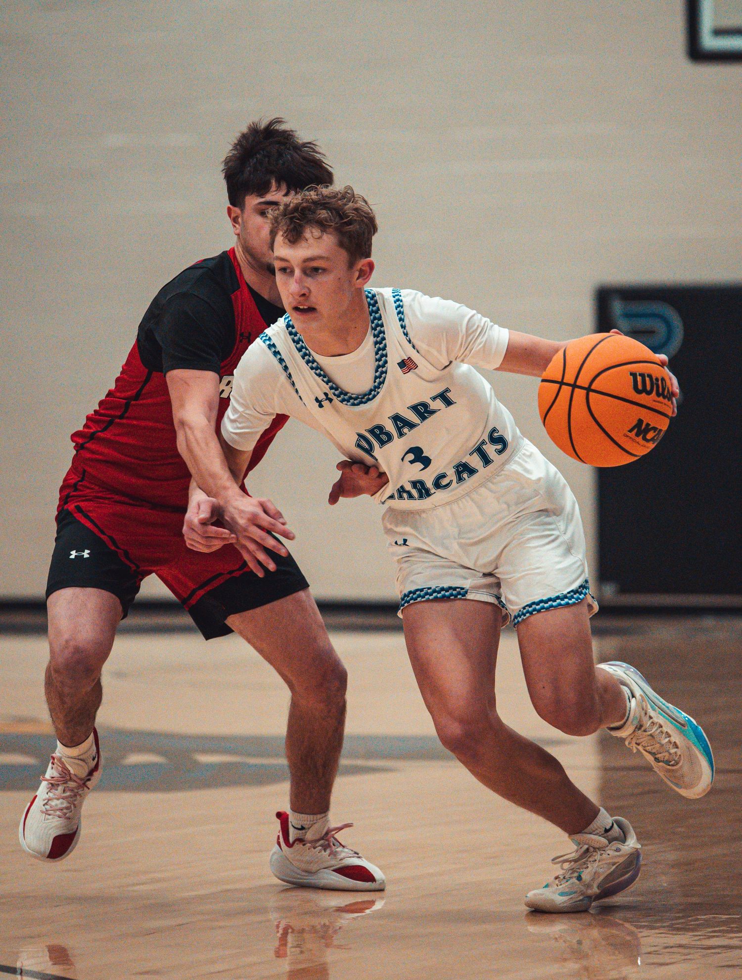 Hobart Bobcats basketball player #3 dribbles past a defender during a high school game.