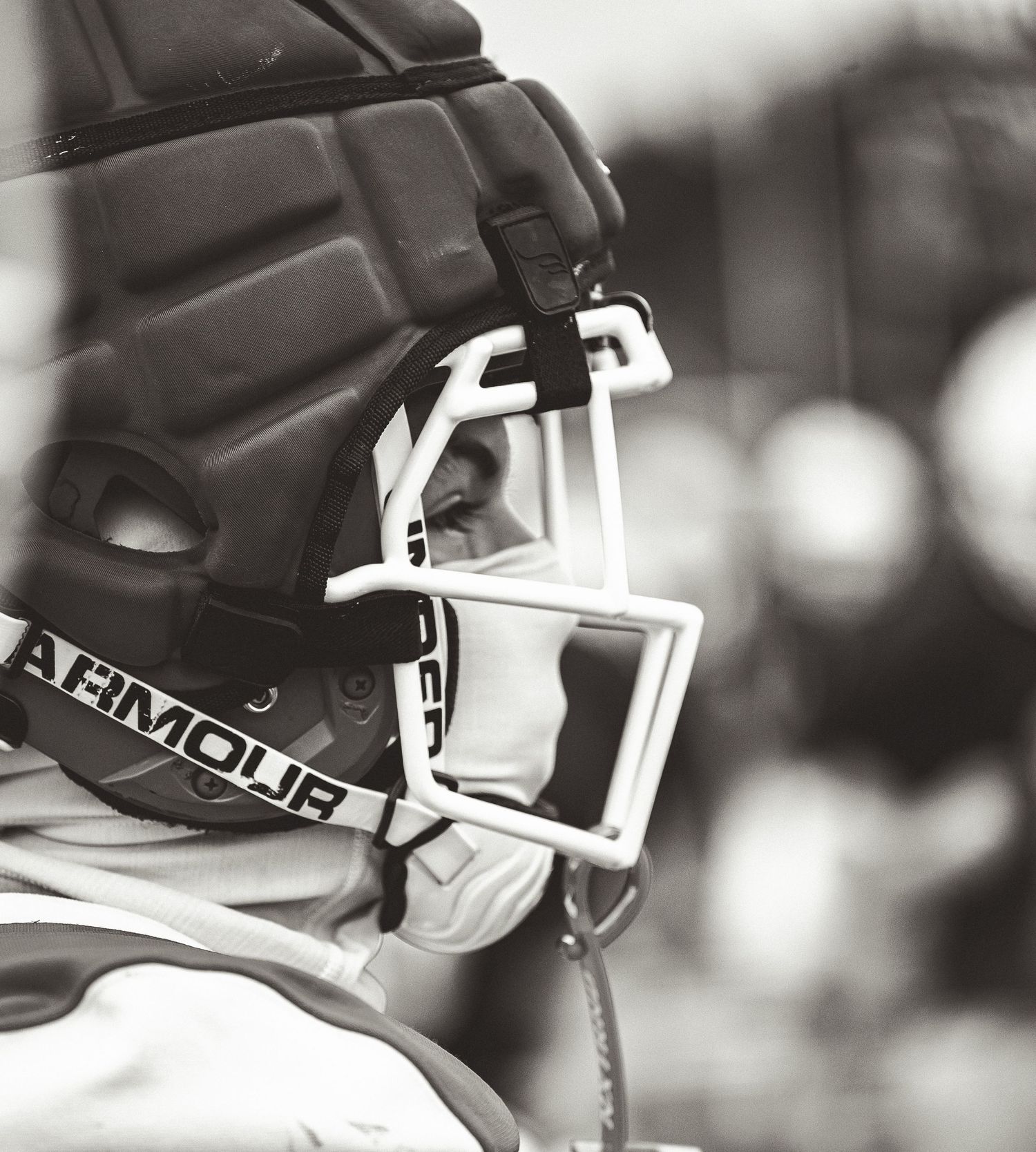 Close-up black and white portrait of a football player wearing an Under Armour helmet.