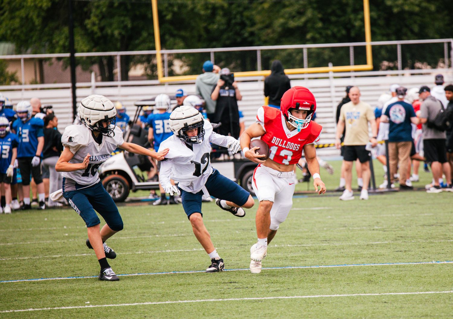 A Bulldogs football player in red uniform evades defenders during an outdoor game.