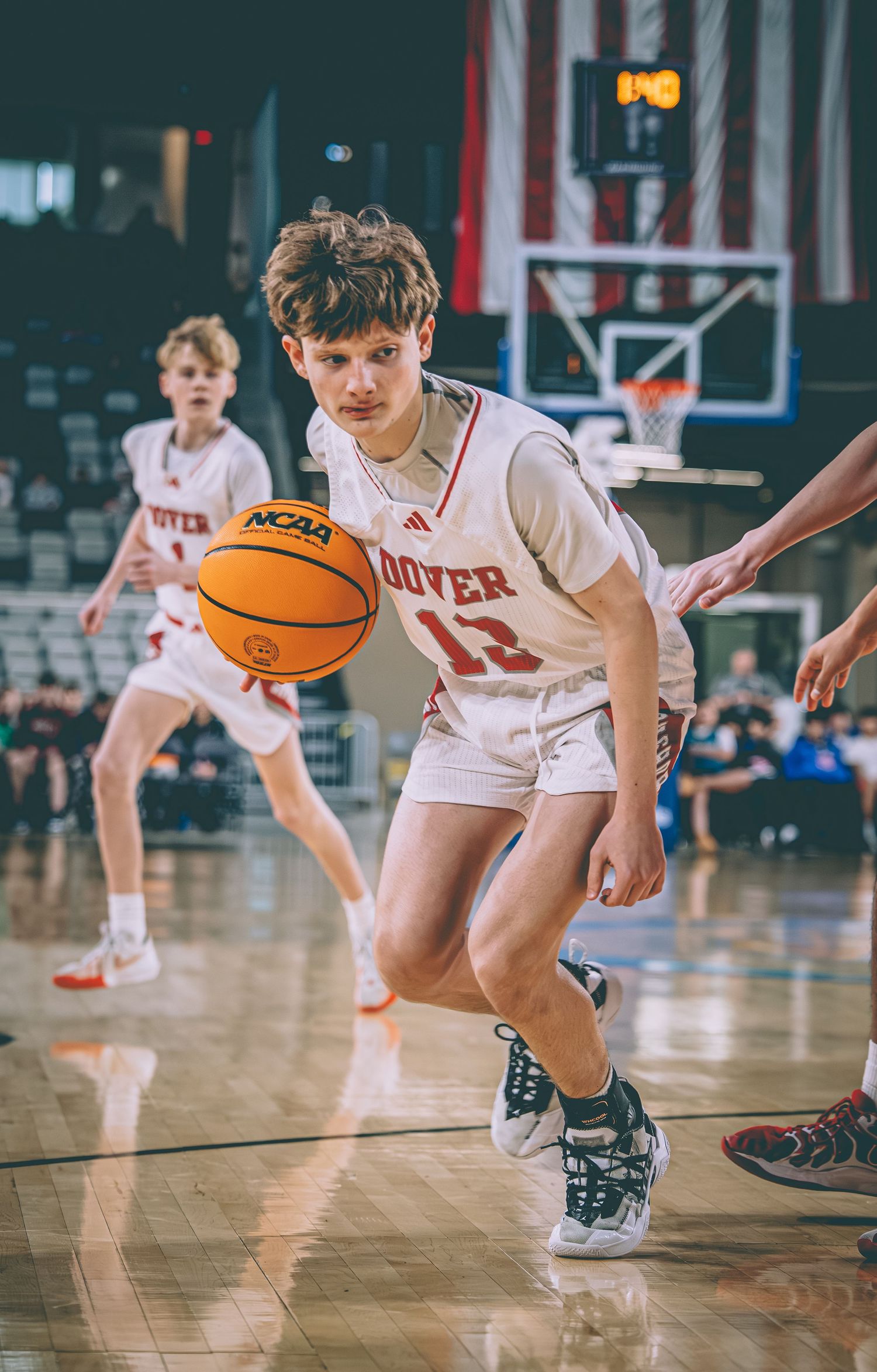 A Dover basketball player dribbles the ball down the court during a competitive game.